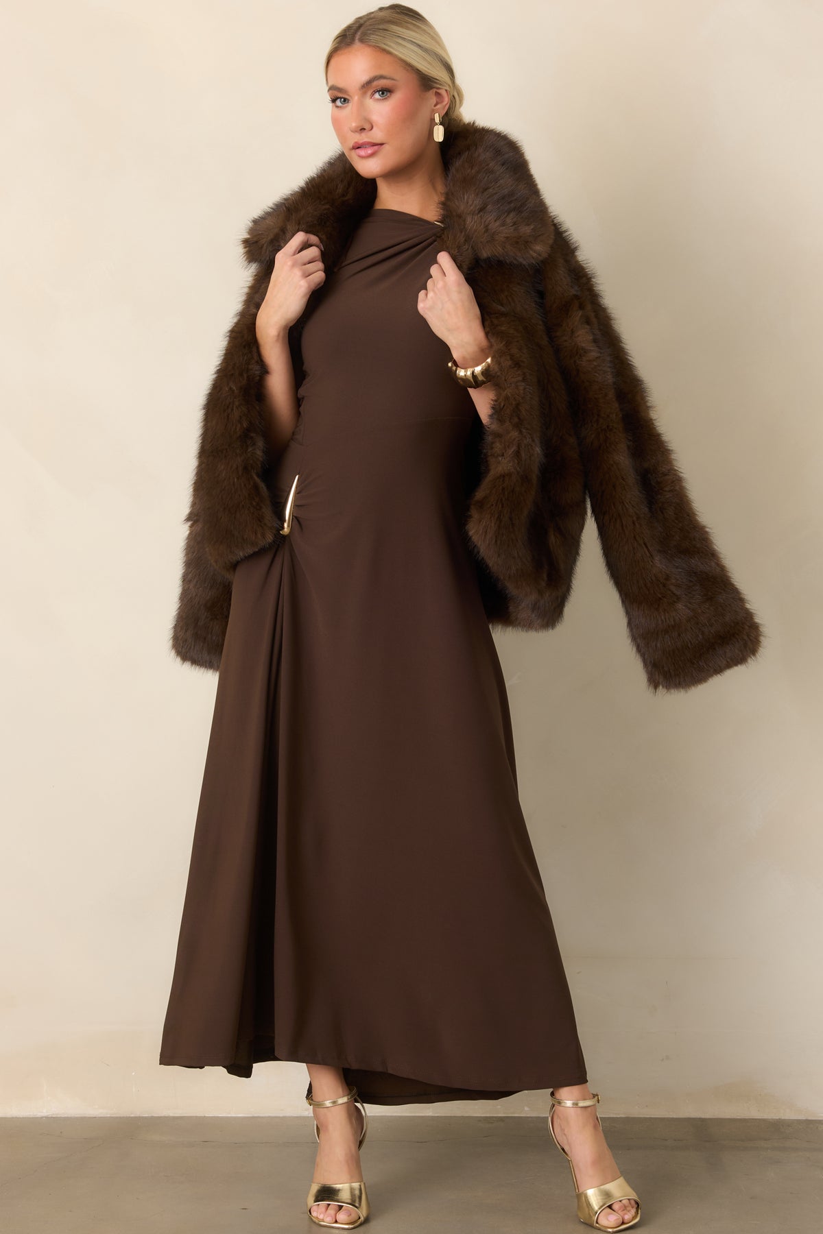 Plush chocolate brown faux fur jacket featuring a generous collar, long sleeves, relaxed silhouette, and front hook closures.