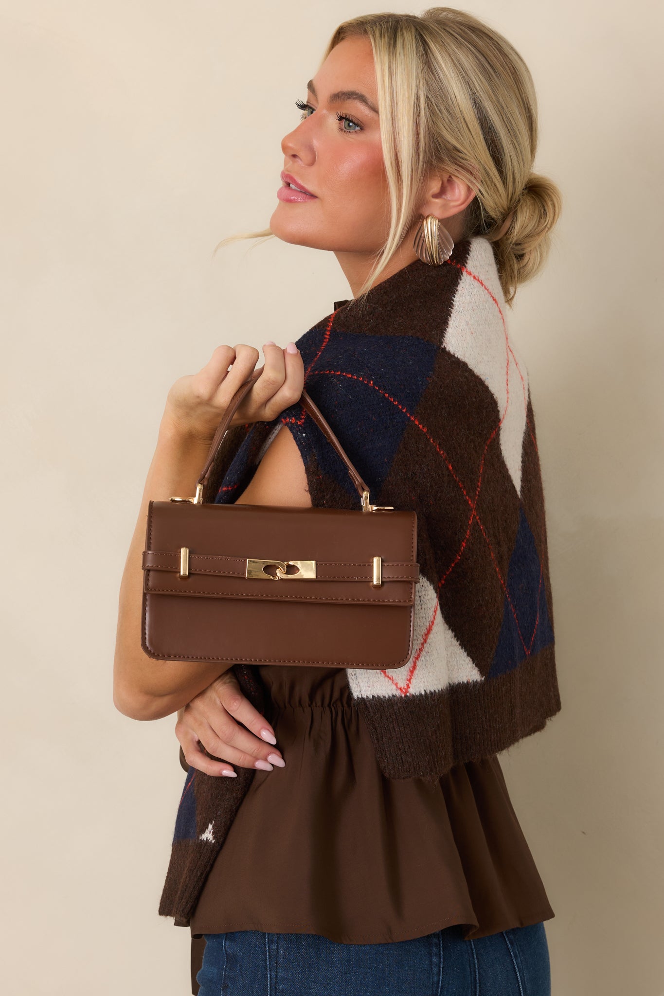 Structured chocolate brown faux leather handbag with polished gold-tone hardware, front belt detail, top handle, and detachable shoulder strap.