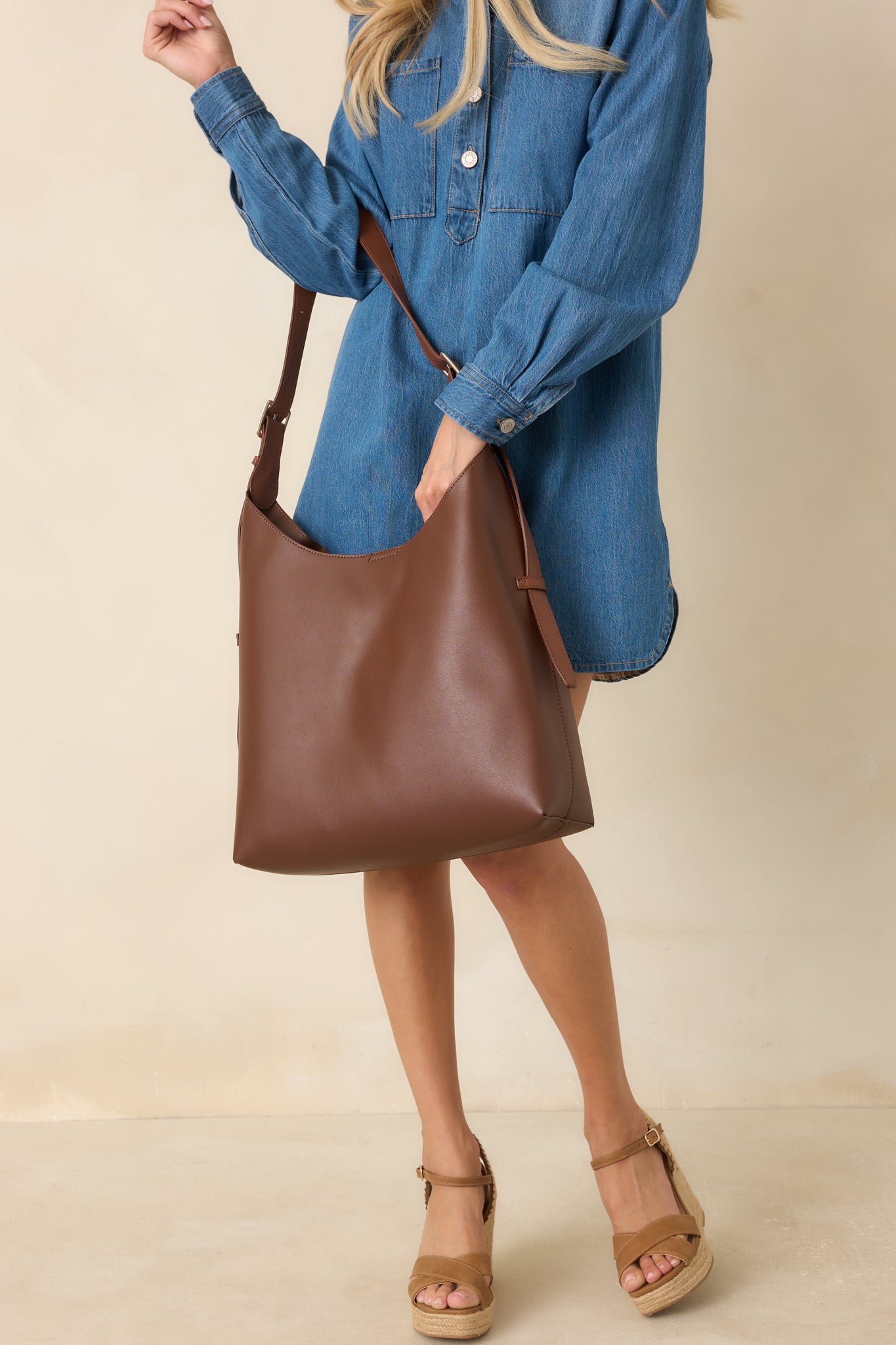 Women's chocolate brown faux leather hobo bag with an adjustable buckle strap and minimalist design.