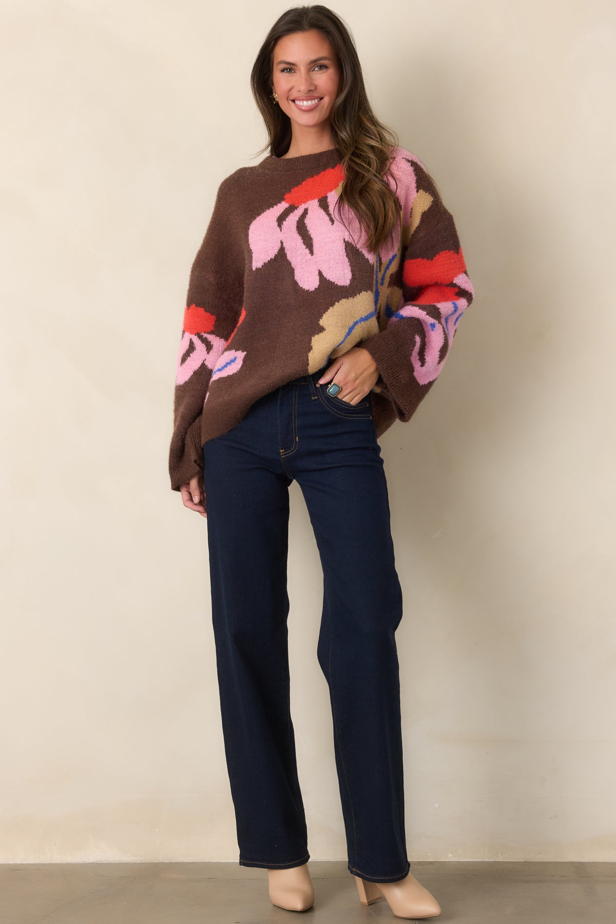 Deep chocolate-brown knit top featuring oversized floral intarsia motifs in pink, red-orange, camel, and cobalt.