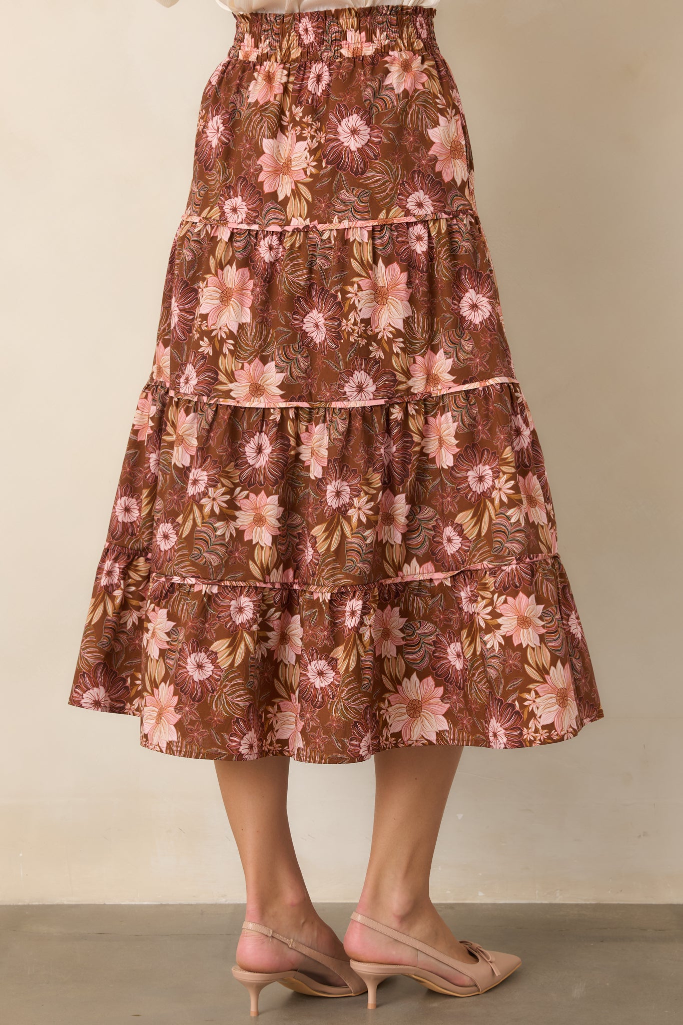 Rear view of the chocolate brown floral midi skirt, showcasing the smocked waistband, tiered construction, and flowing silhouette.