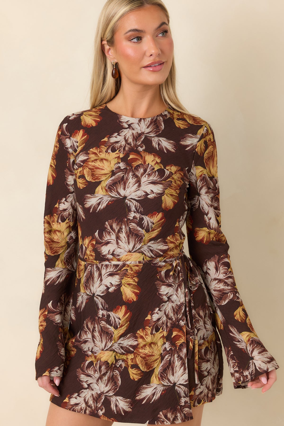 Long flared sleeves complement the chocolate brown fabric decorated with golden yellow and rust blossoms.