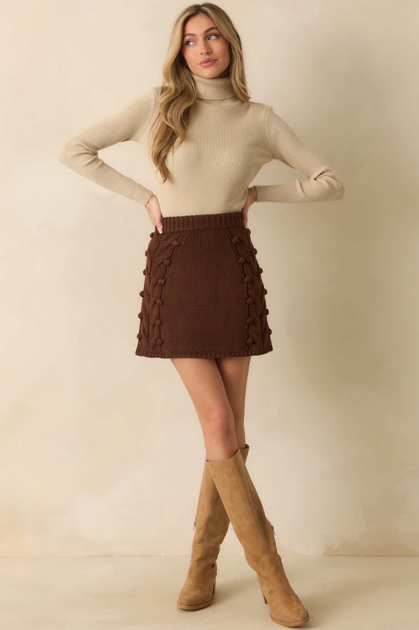 Chocolate brown mini skirt with a fitted silhouette, featuring chunky cable knit and playful bobble detailing.