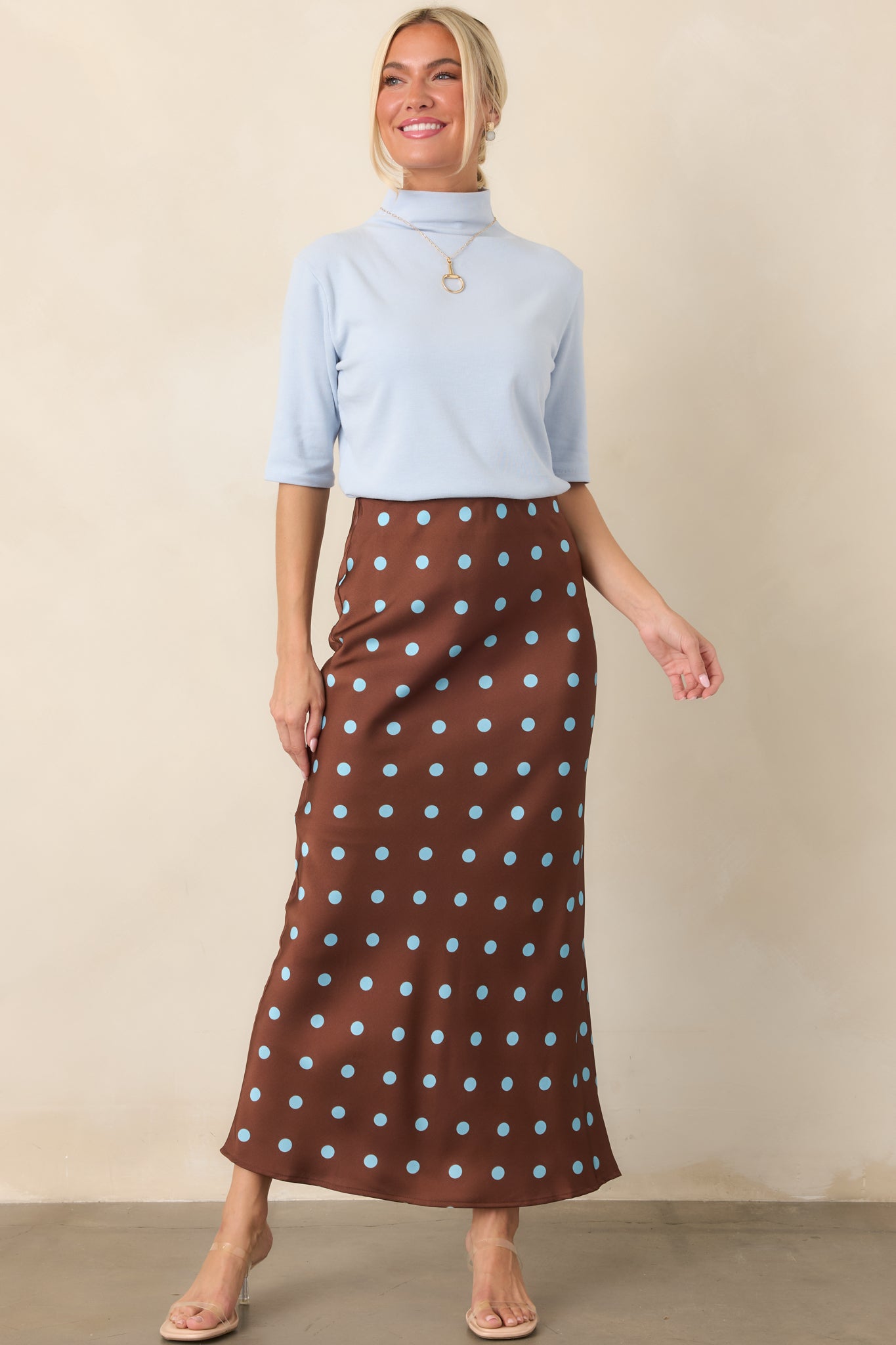 Chocolate brown satin midi skirt featuring light blue polka dots, a flowing bias-cut silhouette, and comfortable elastic waistband.