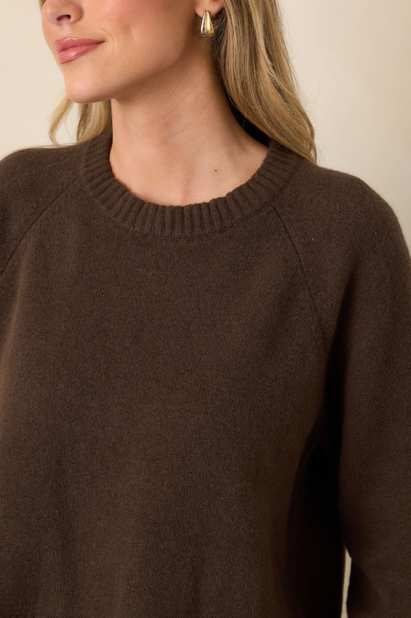Detailed view highlighting the soft chocolate brown knit, ribbed neckline, and softly gathered raglan sleeve construction.