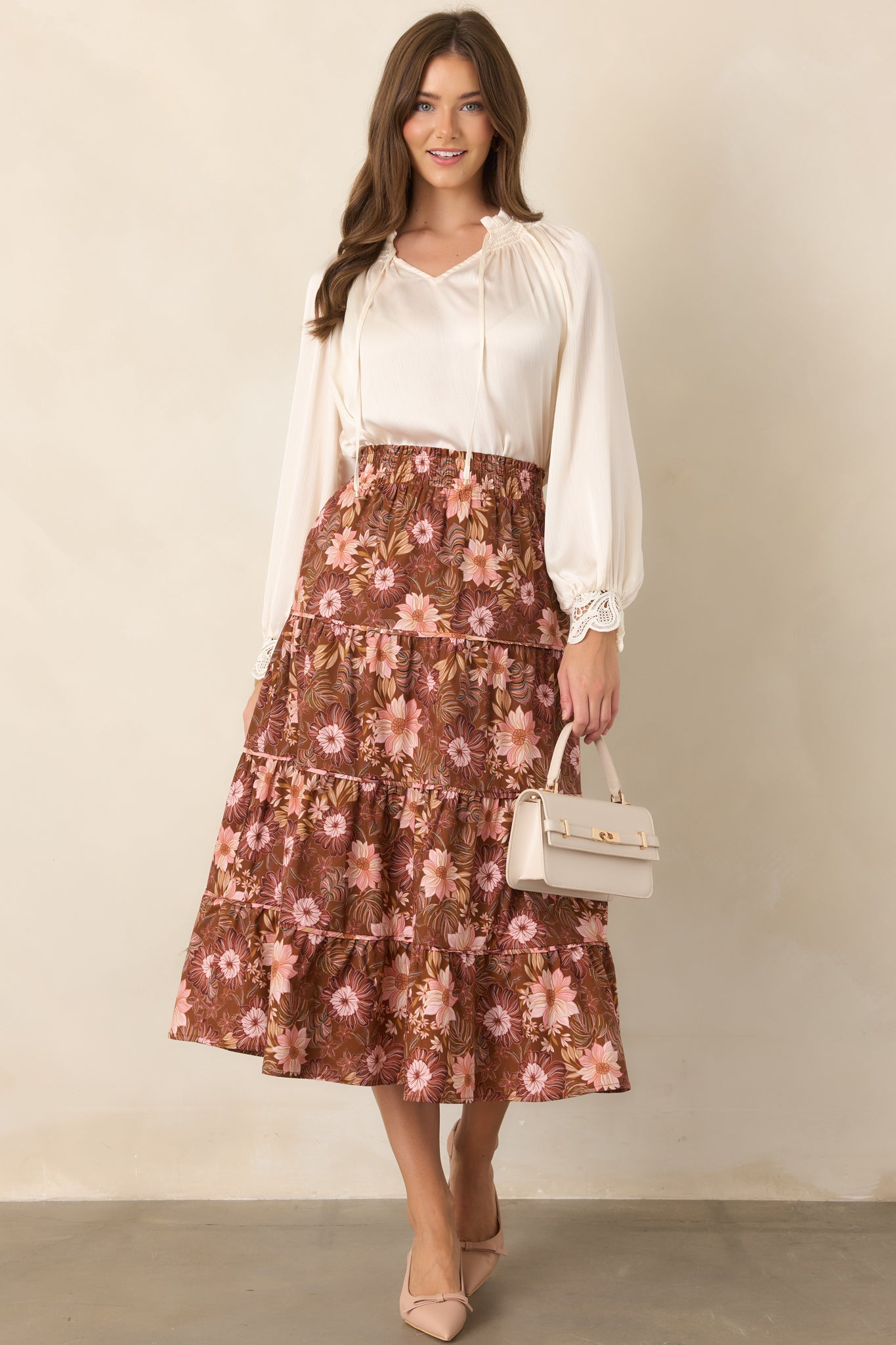 Chocolate brown tiered midi skirt with an allover floral pattern in soft pink, burgundy, and muted green, creating a voluminous flowing shape.

