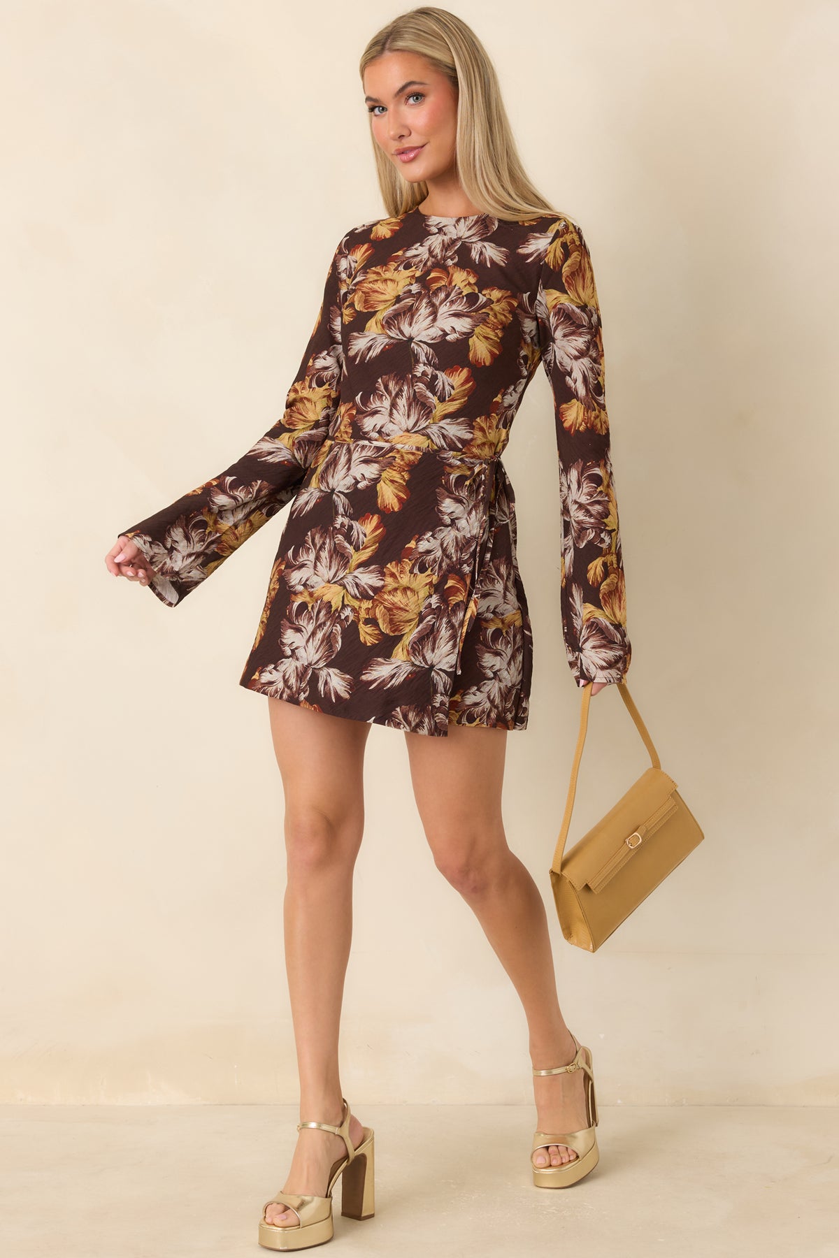 Chocolate brown mini dress with warm yellow and rust florals, romantic bell sleeves, and a draped wrap skirt.