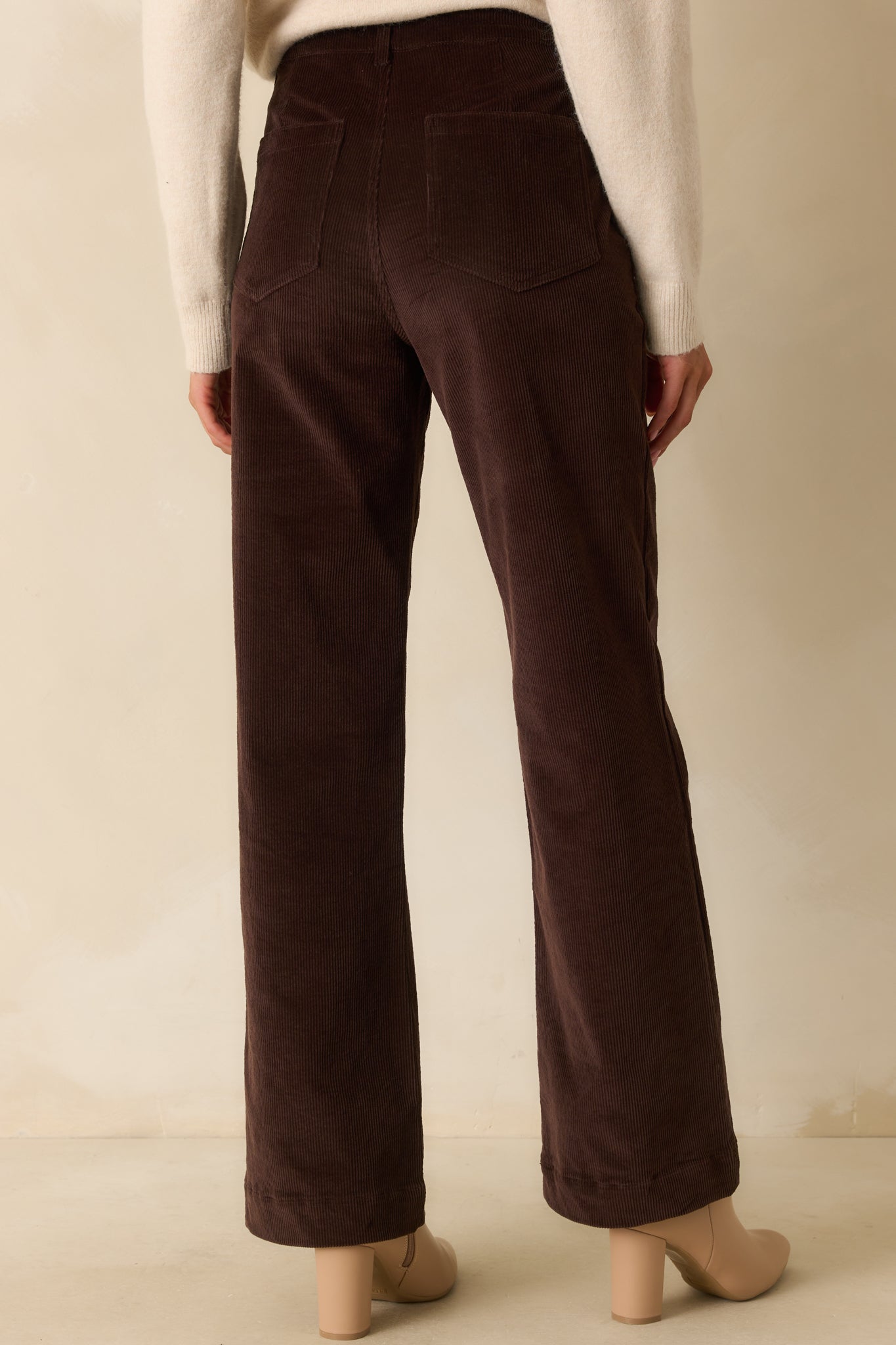 Rear view of chocolate brown corduroy pants featuring back patch pockets and straight-leg fit.