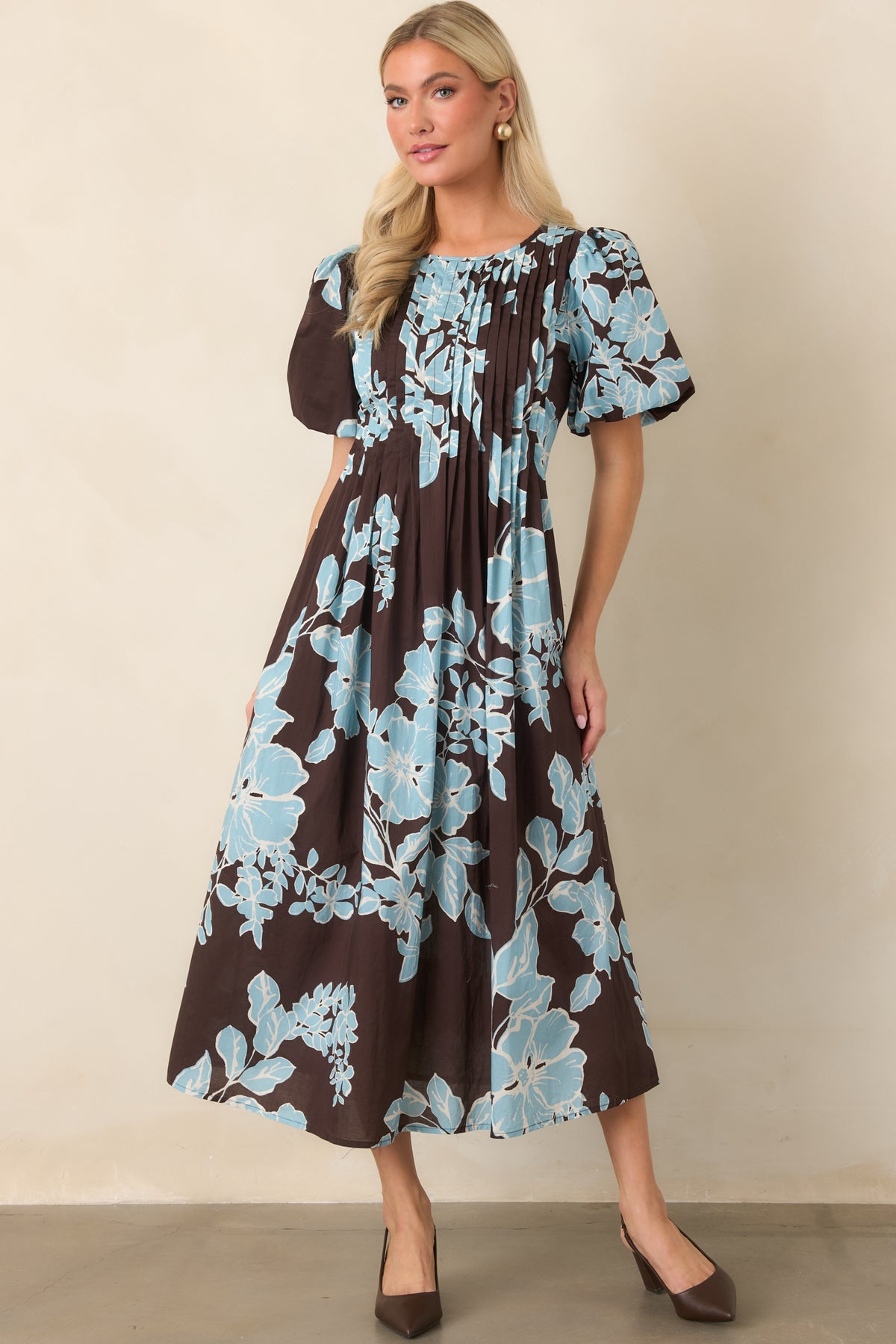 Chocolate floral dress highlighting the contrast between oversized blue blooms and its gently flared midi silhouette.