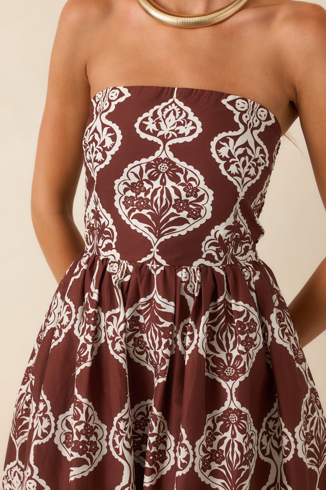 Close-up view of the chocolate brown and ivory dress highlighting the medallion print and border hem detailing.