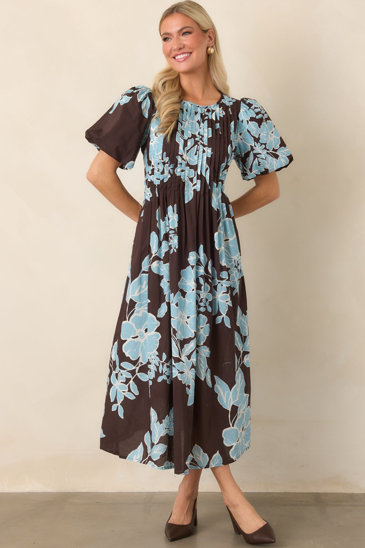 Chocolate dress with oversized blue blooms, short puff sleeves, and a softly flared midi skirt.