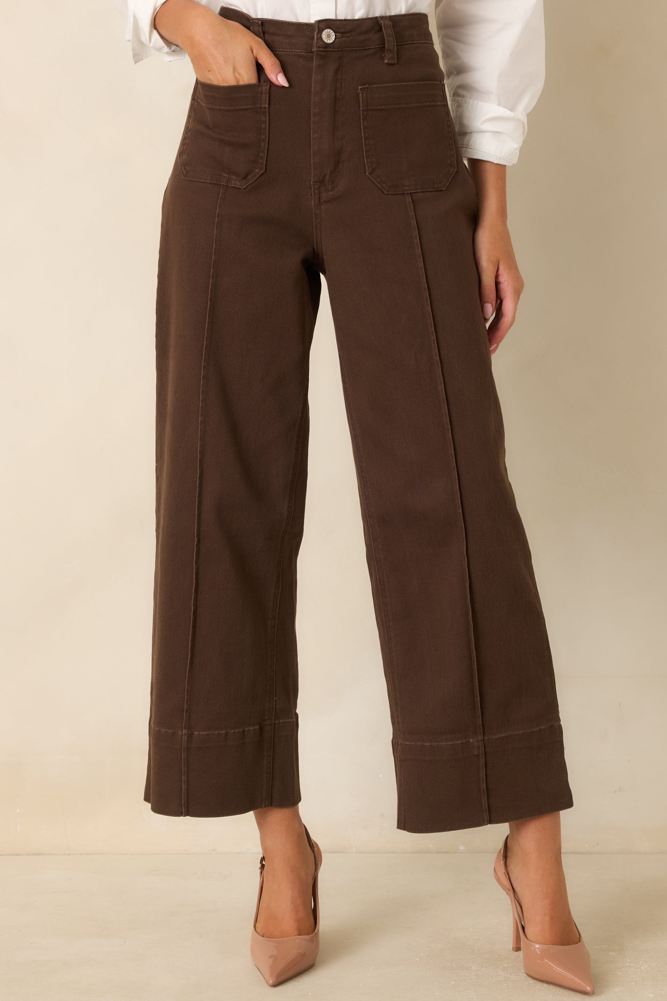 Front detail of the chocolate pants showcasing the pressed center seams, smooth texture, and wide cuff hems.
