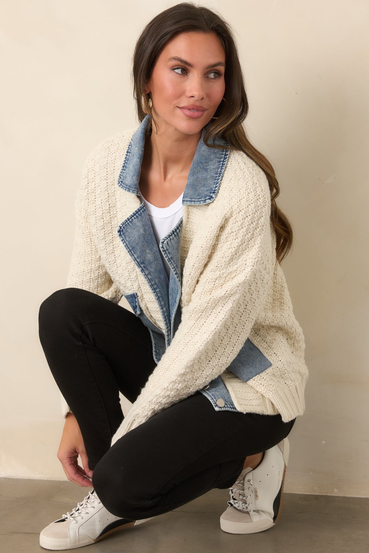 Chunky ivory knit jacket showcasing denim trim and a relaxed layered silhouette.