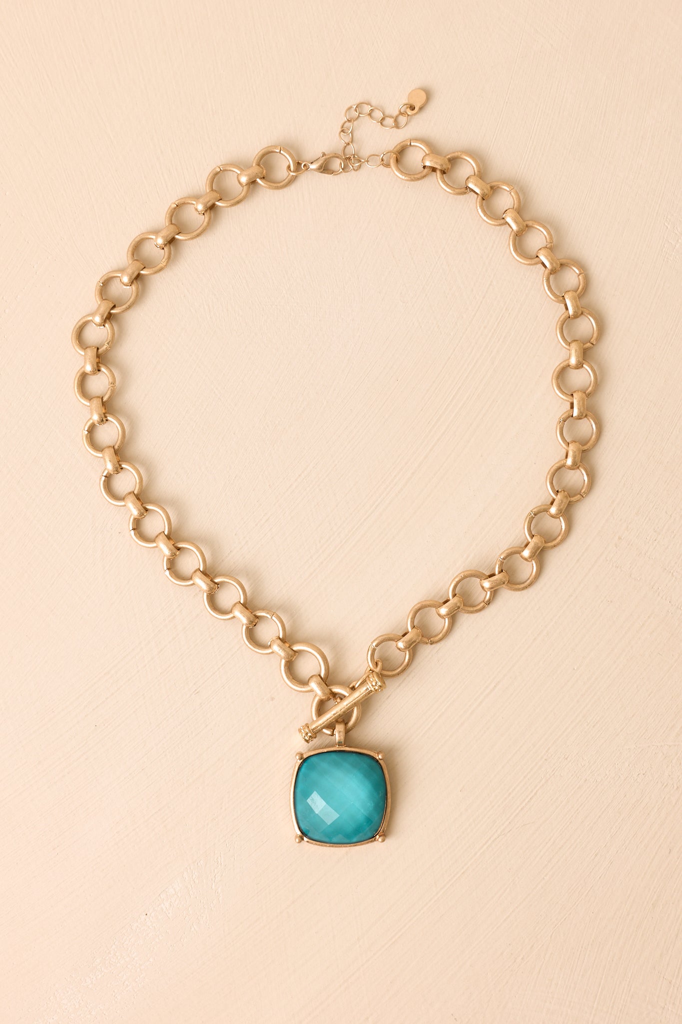 Bold chain necklace featuring a polished teal pendant and chunky matte gold links.