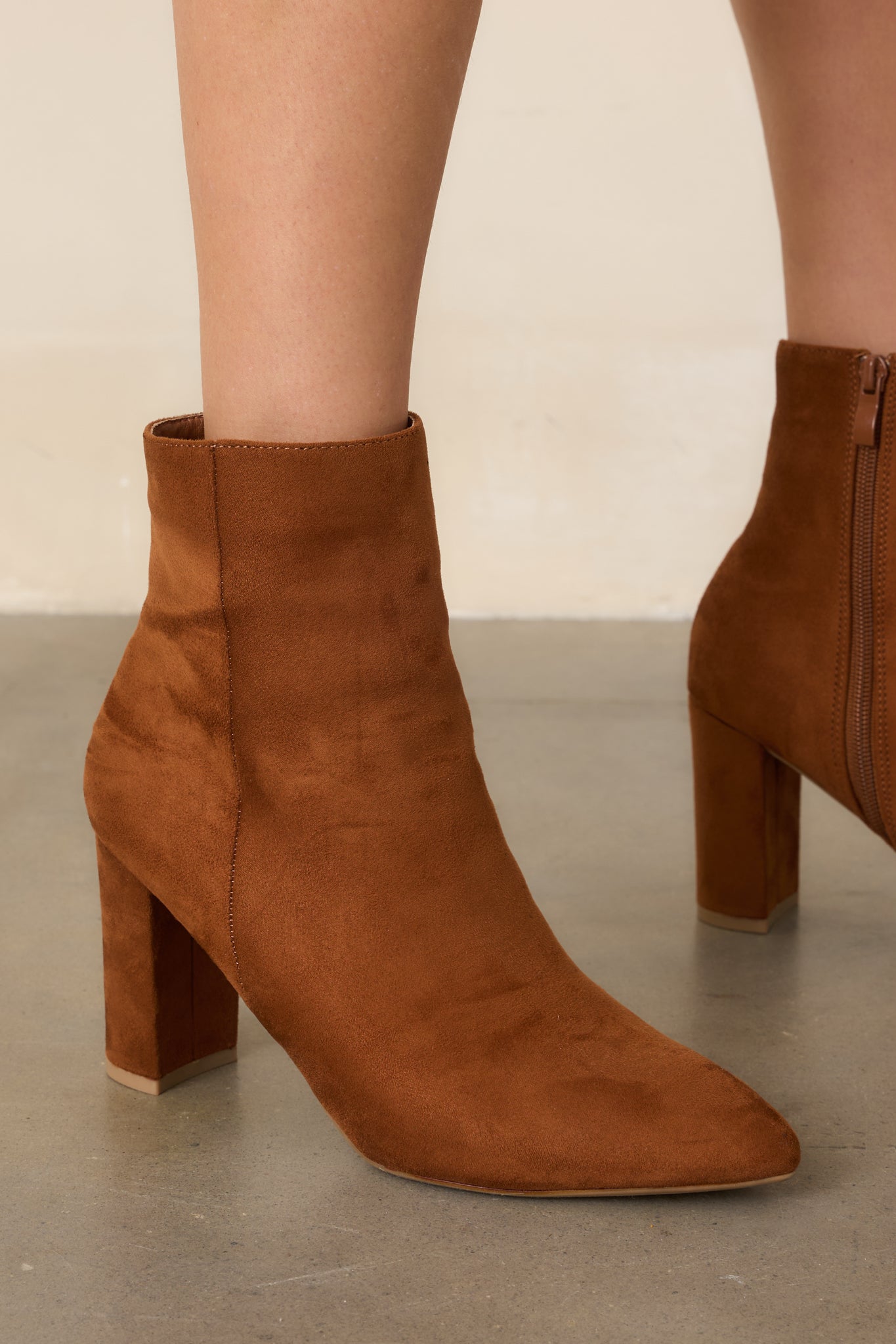 Cinnamon brown ankle boots crafted from faux suede with pointed toes, outer seam detailing, inner zippers, and block heels.