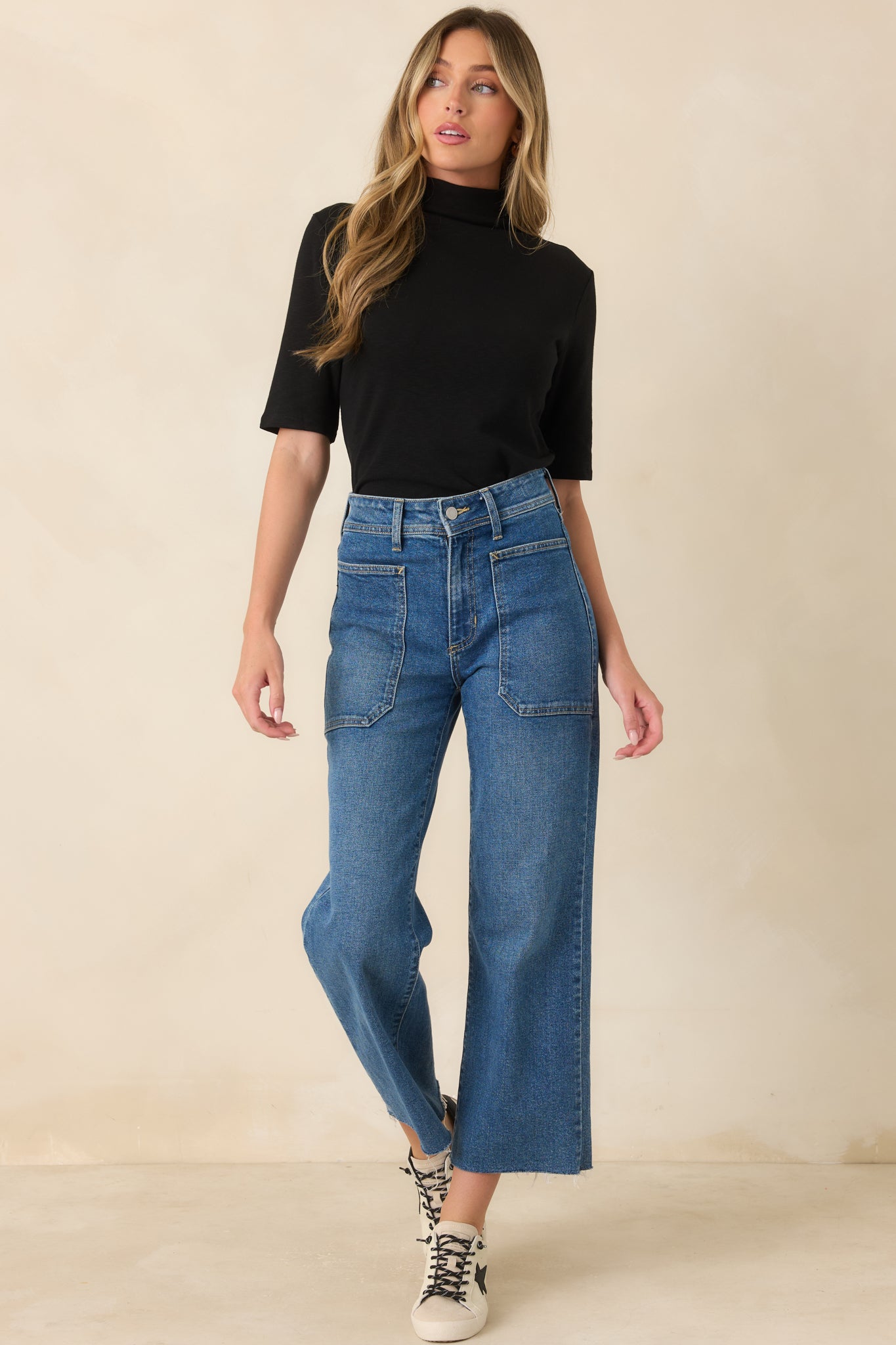 Classic black top crafted with a soft stretch knit, elegant mock neckline, structured elbow-length sleeves, and a sleek streamlined shape.