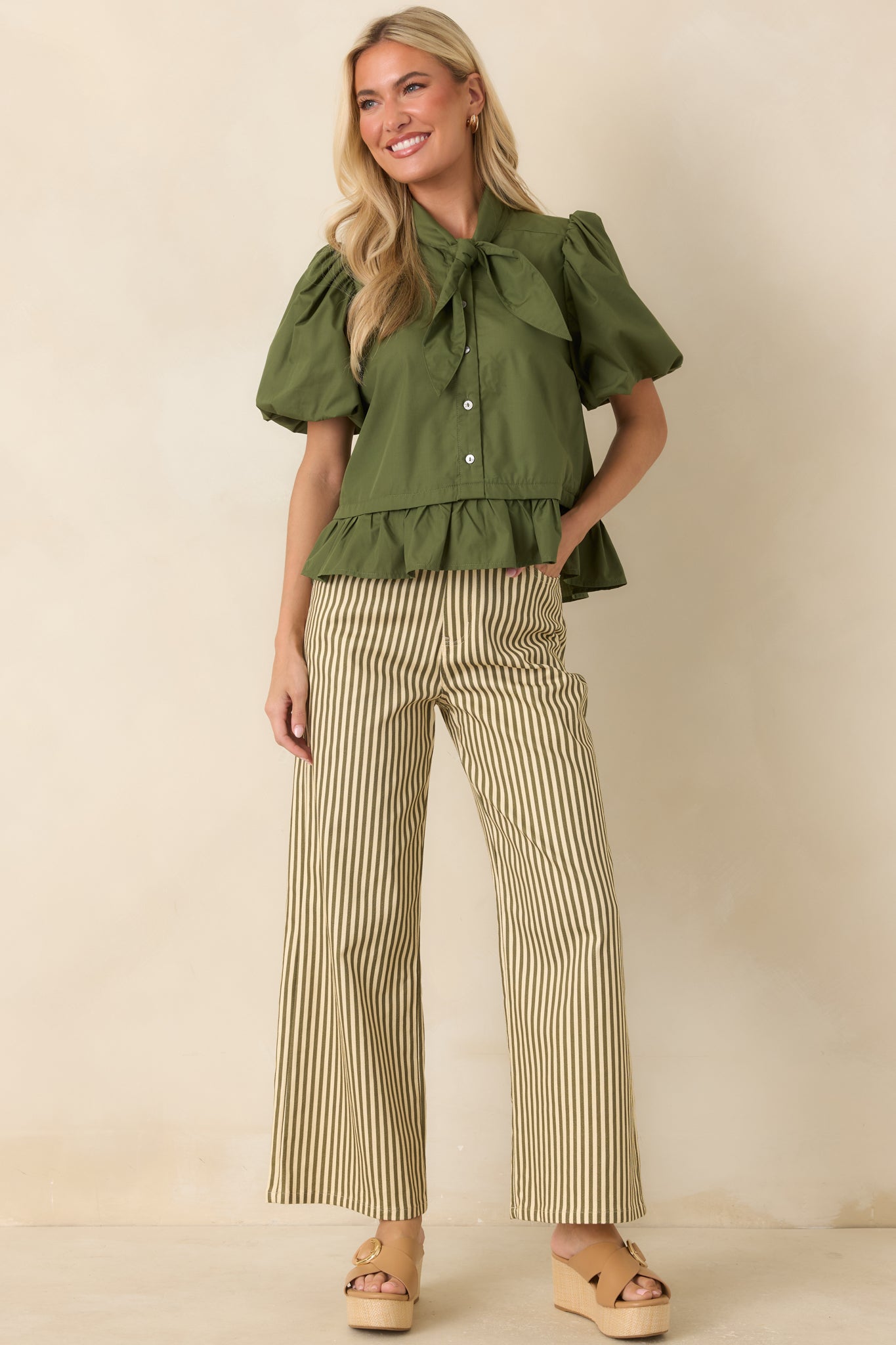 Moss green blouse with a classic bow tie detail, structured puff sleeves, and a flattering peplum silhouette.
