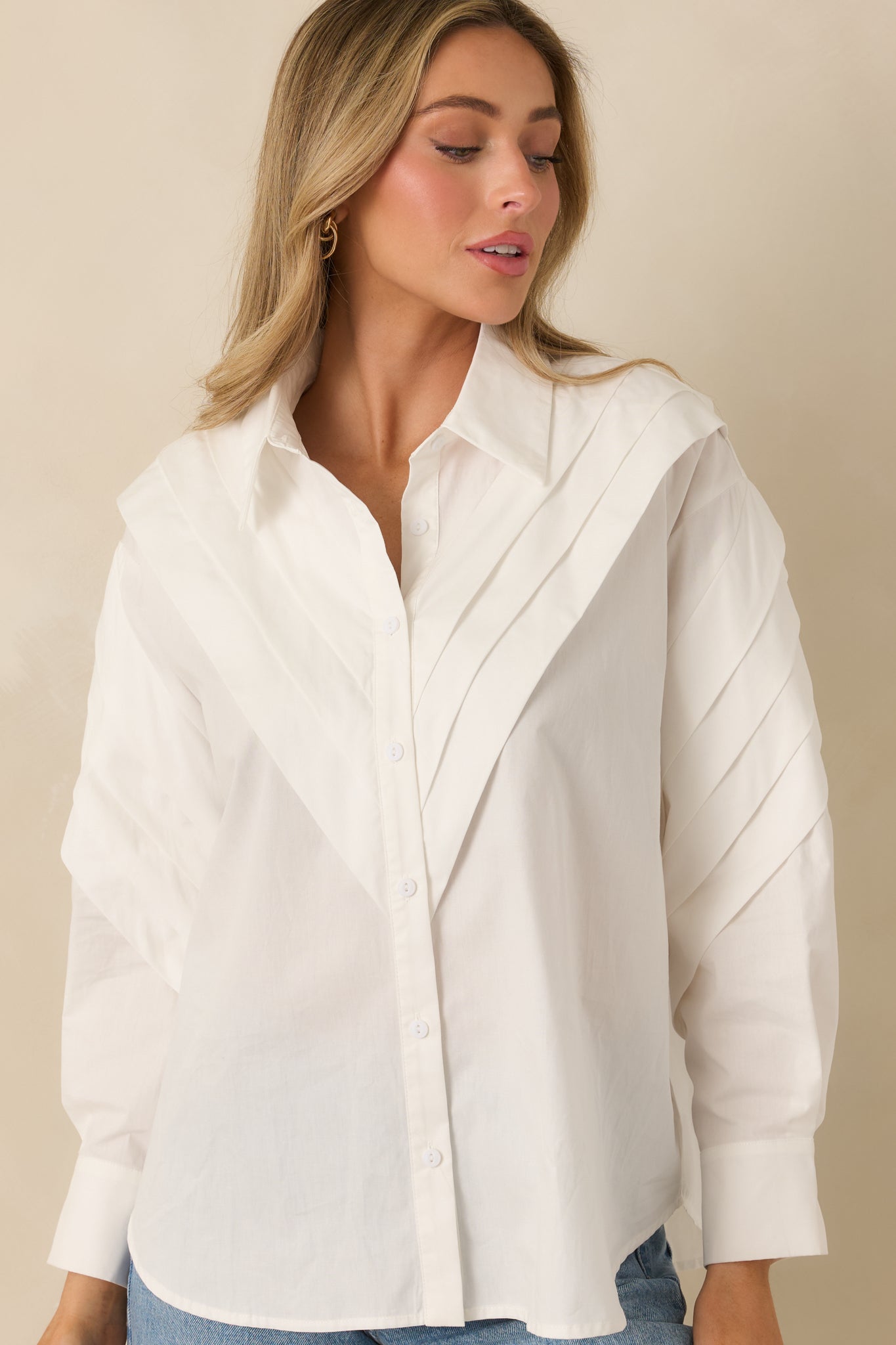 Classic collar and front button closure on a white cotton blouse with subtle structure.