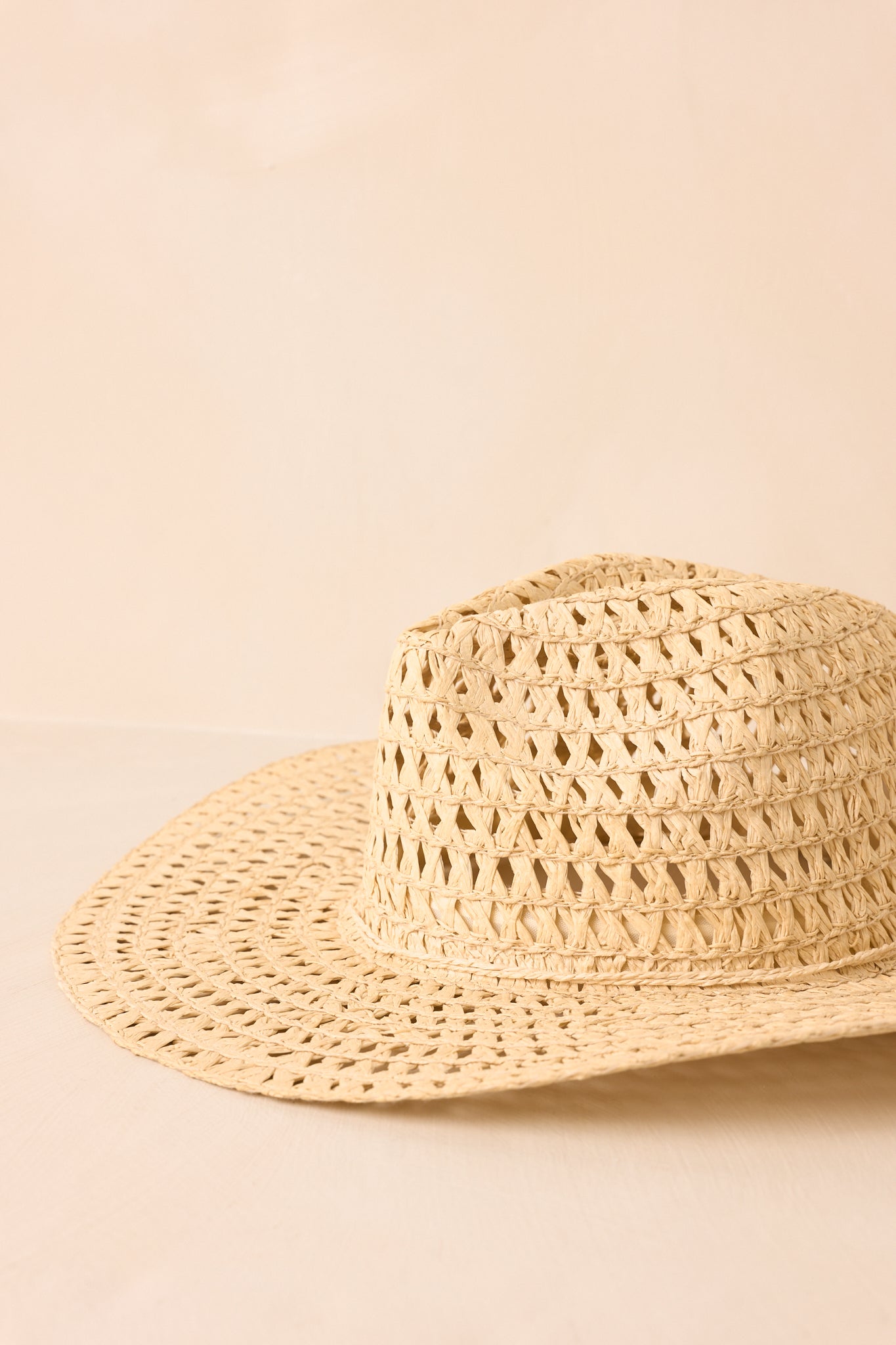 Classic ivory cowboy hat showcasing a structured crown and breathable open-weave straw texture against a beige background.