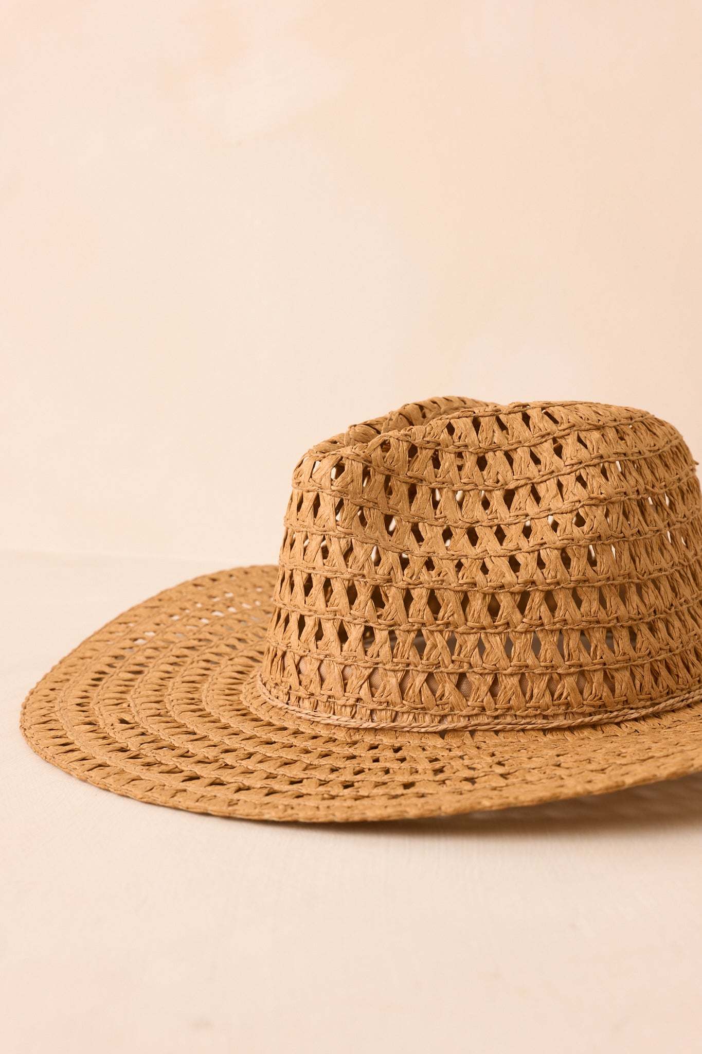 Classic cowboy hat showcasing a structured crown and lightweight straw construction against a beige background.