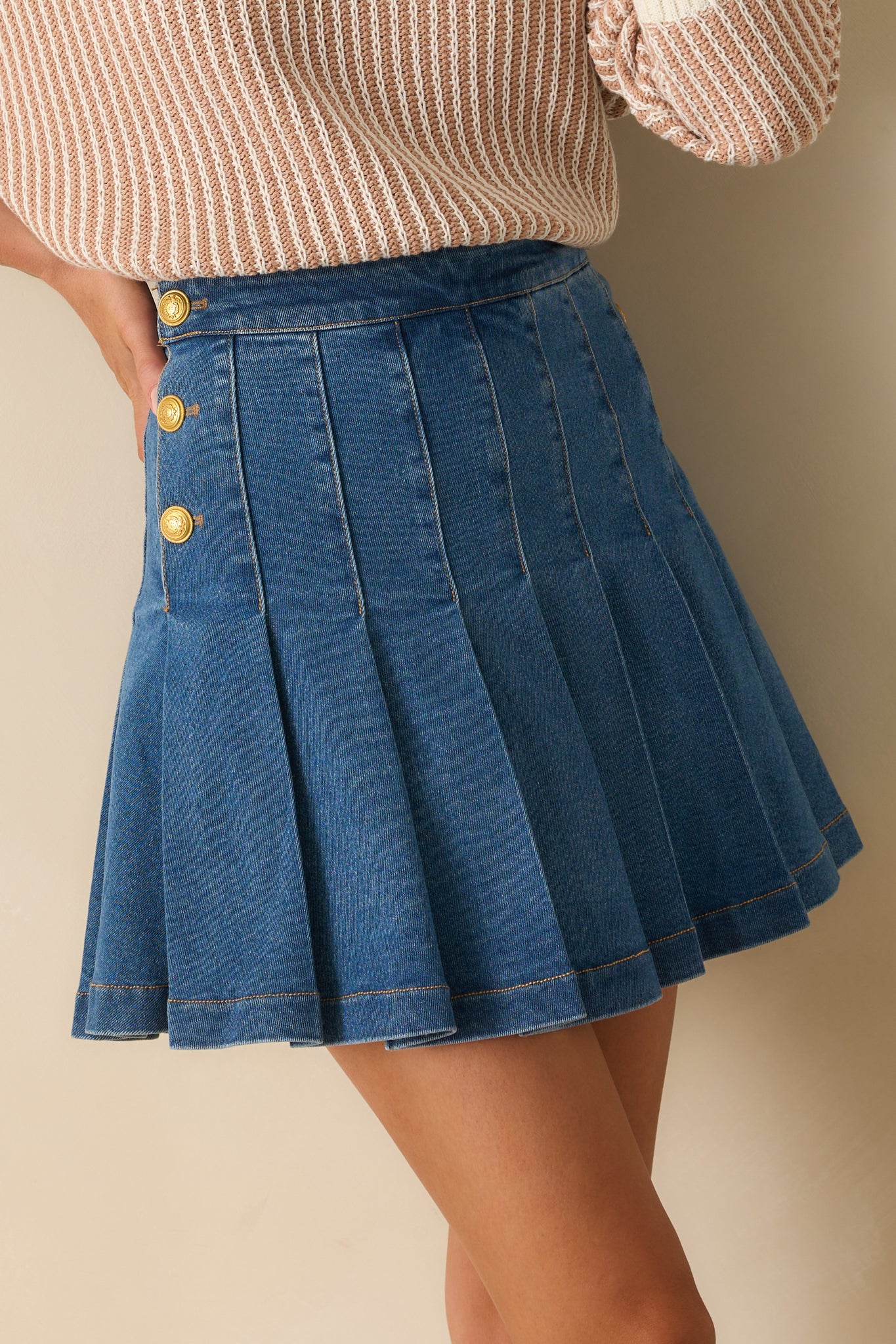 Close-up angled pose showing the detailed embossing on the gold buttons and the grain of the denim fabric.