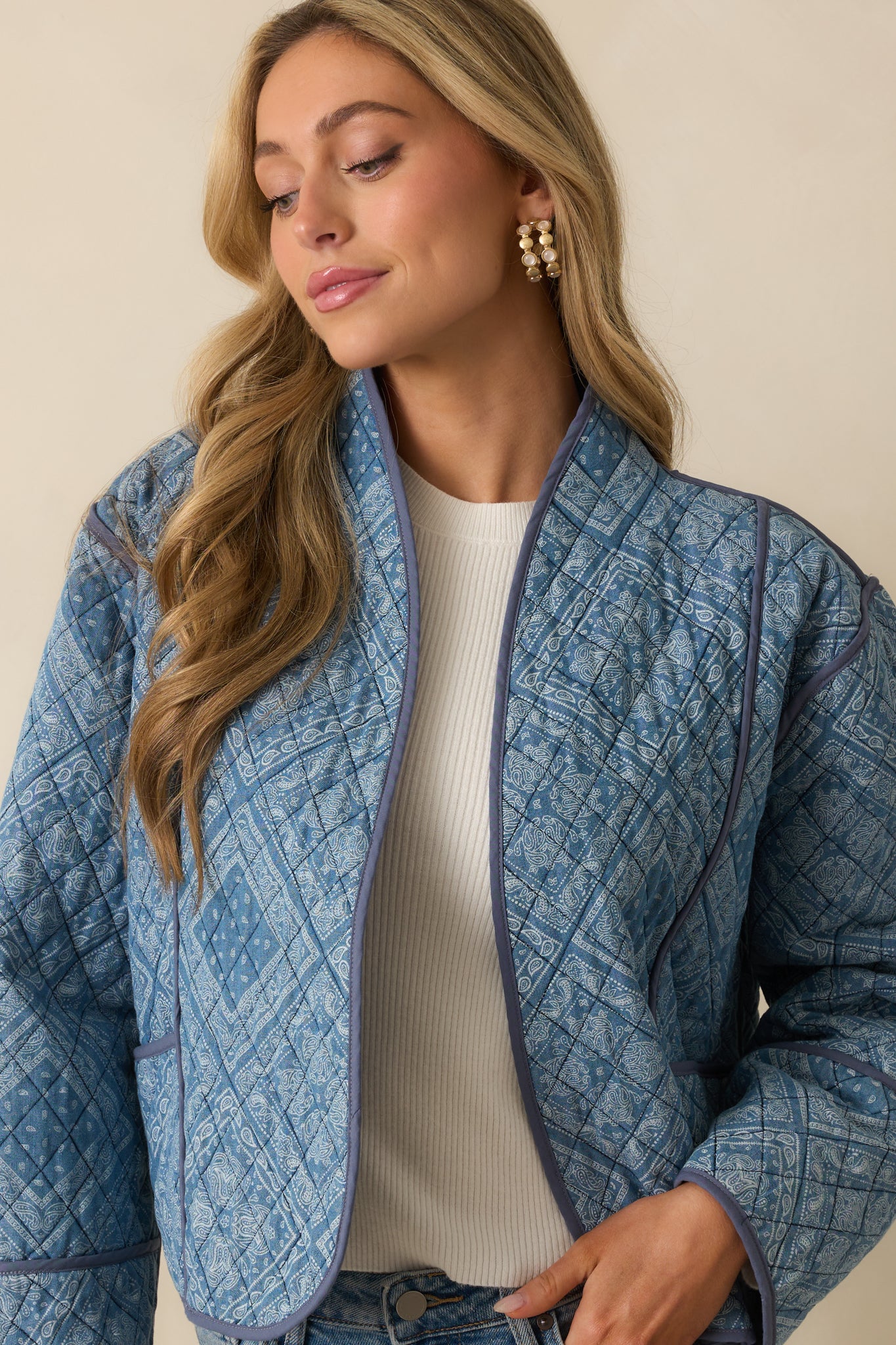 Close crop of the light blue jacket, emphasizing the geometric paisley print and quilting.