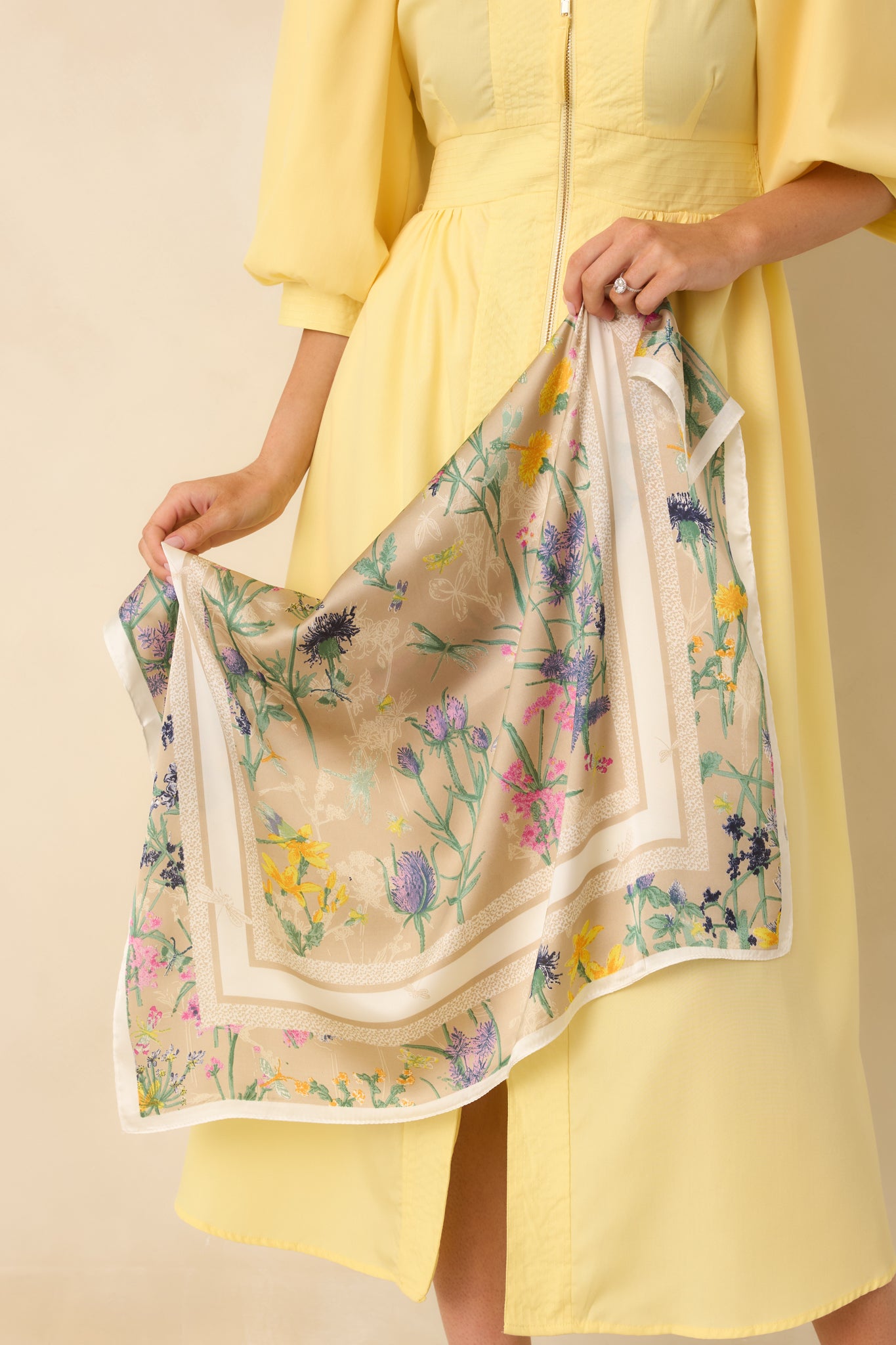 Close cropped section of the beige scarf showing the floral motif and shiny satin texture.