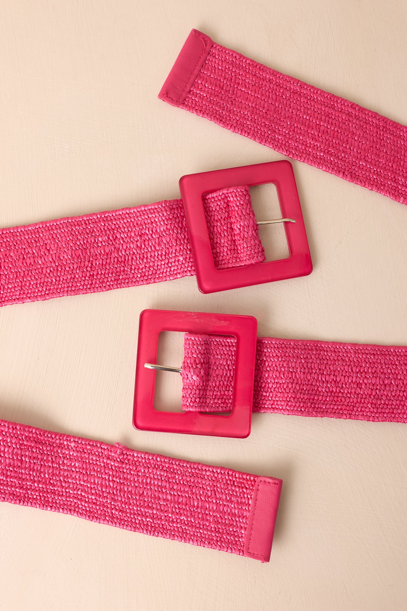 Close cropped angle of hot pink belt showing square acrylic buckle and woven strap
