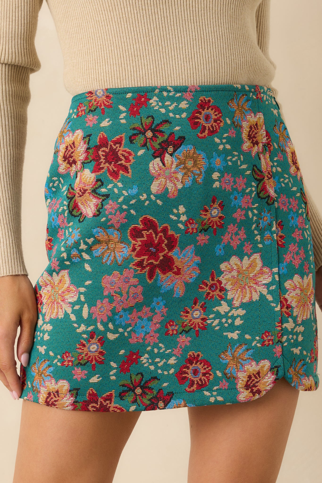 Close-up detail of the teal-green skirt emphasizing the woven fabric texture and colorful floral print.