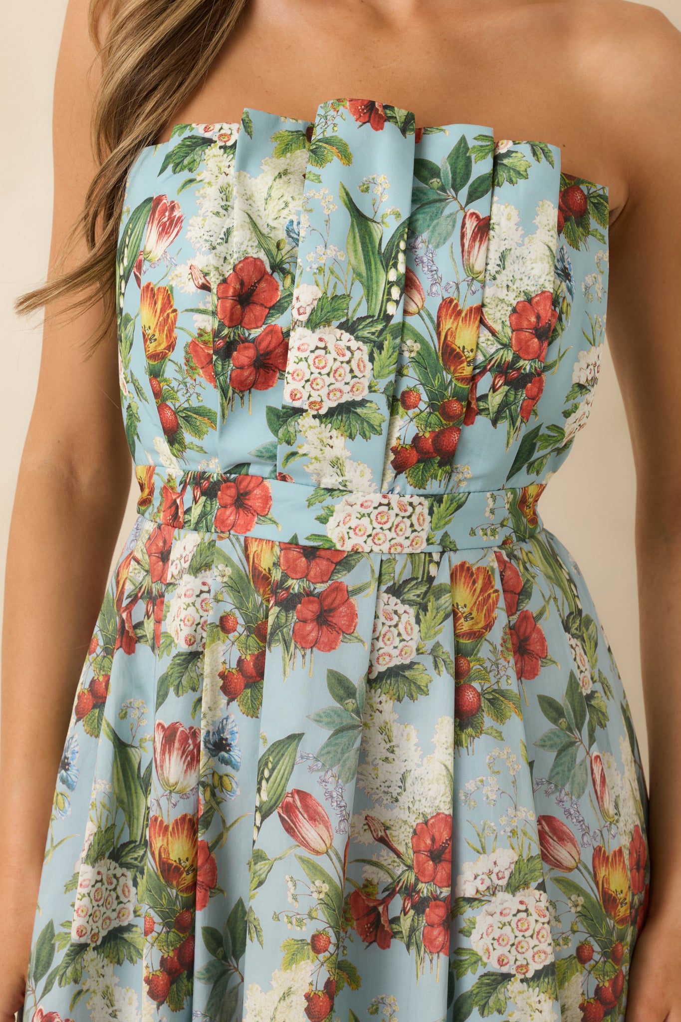 Close-up detail of the blue floral dress showing pleated bodice construction and printed fabric texture.