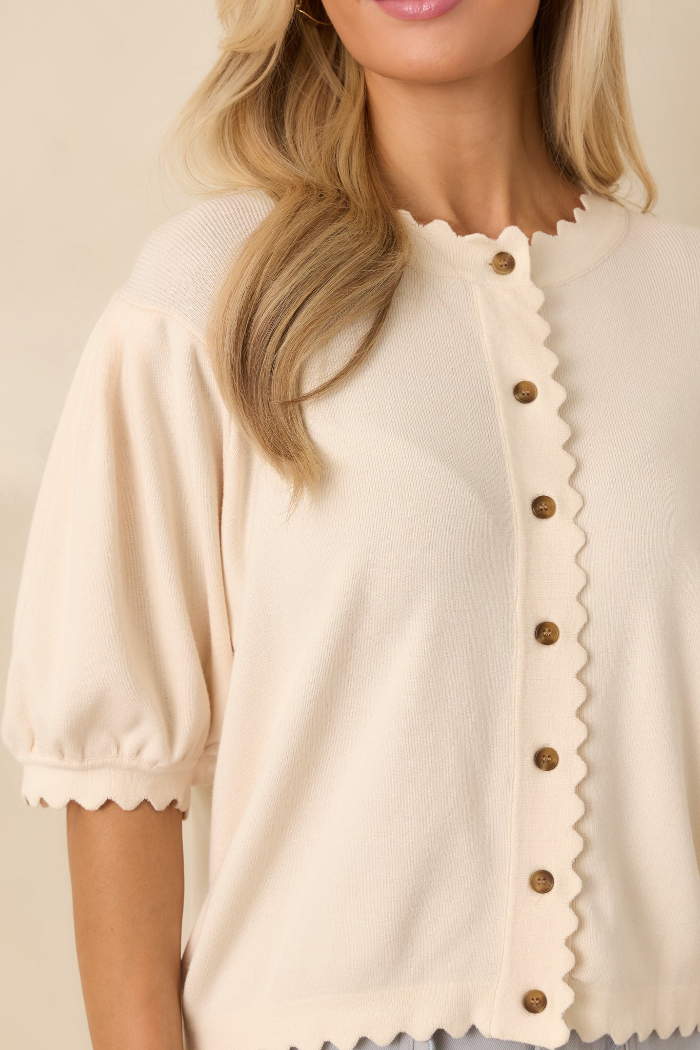 Ultra close-knit detail showing the button hardware and textured ivory knit with scalloped placket accents.