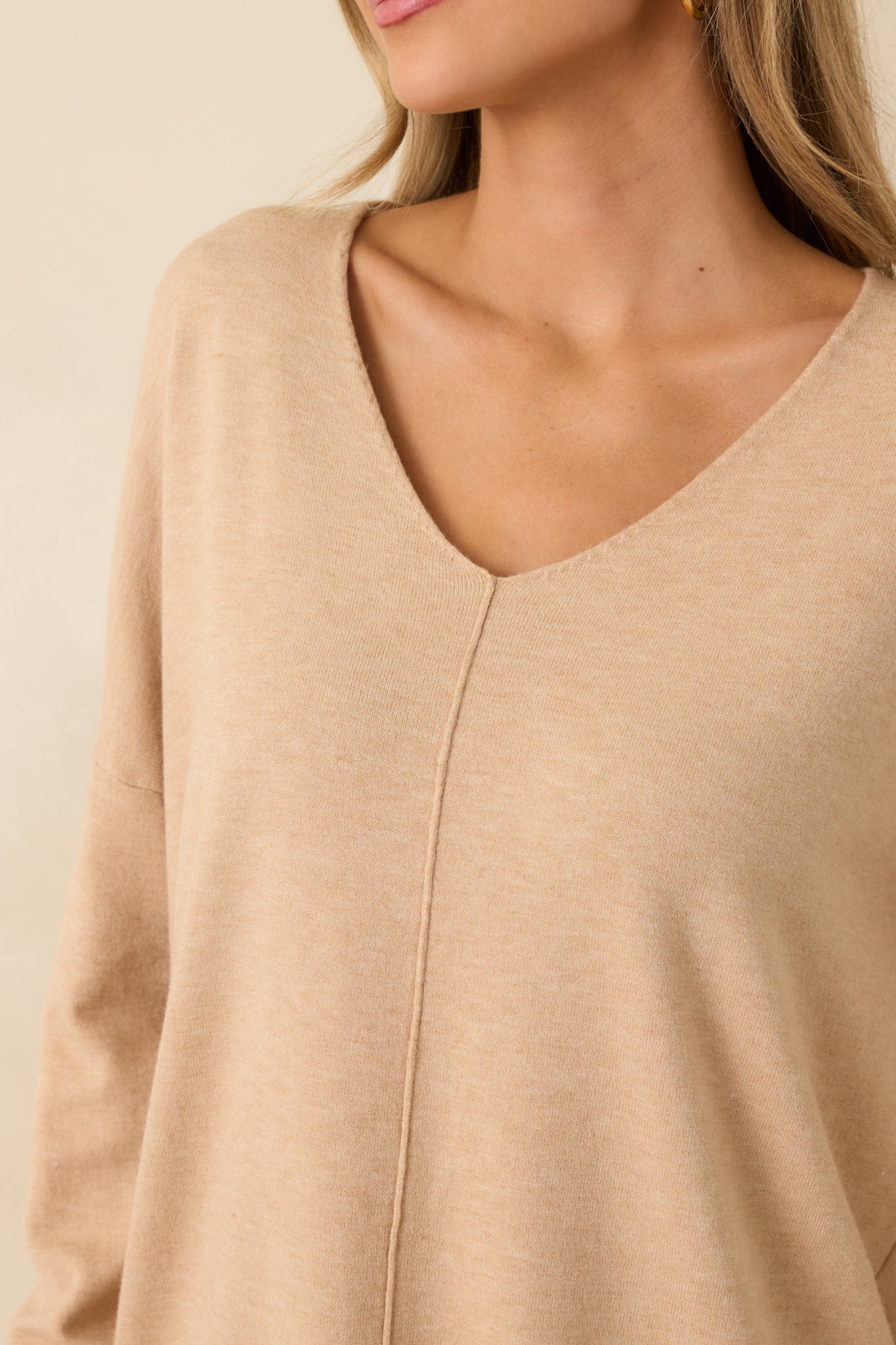 Close detail of the light taupe knit fabric showing subtle texture and soft V-neckline.