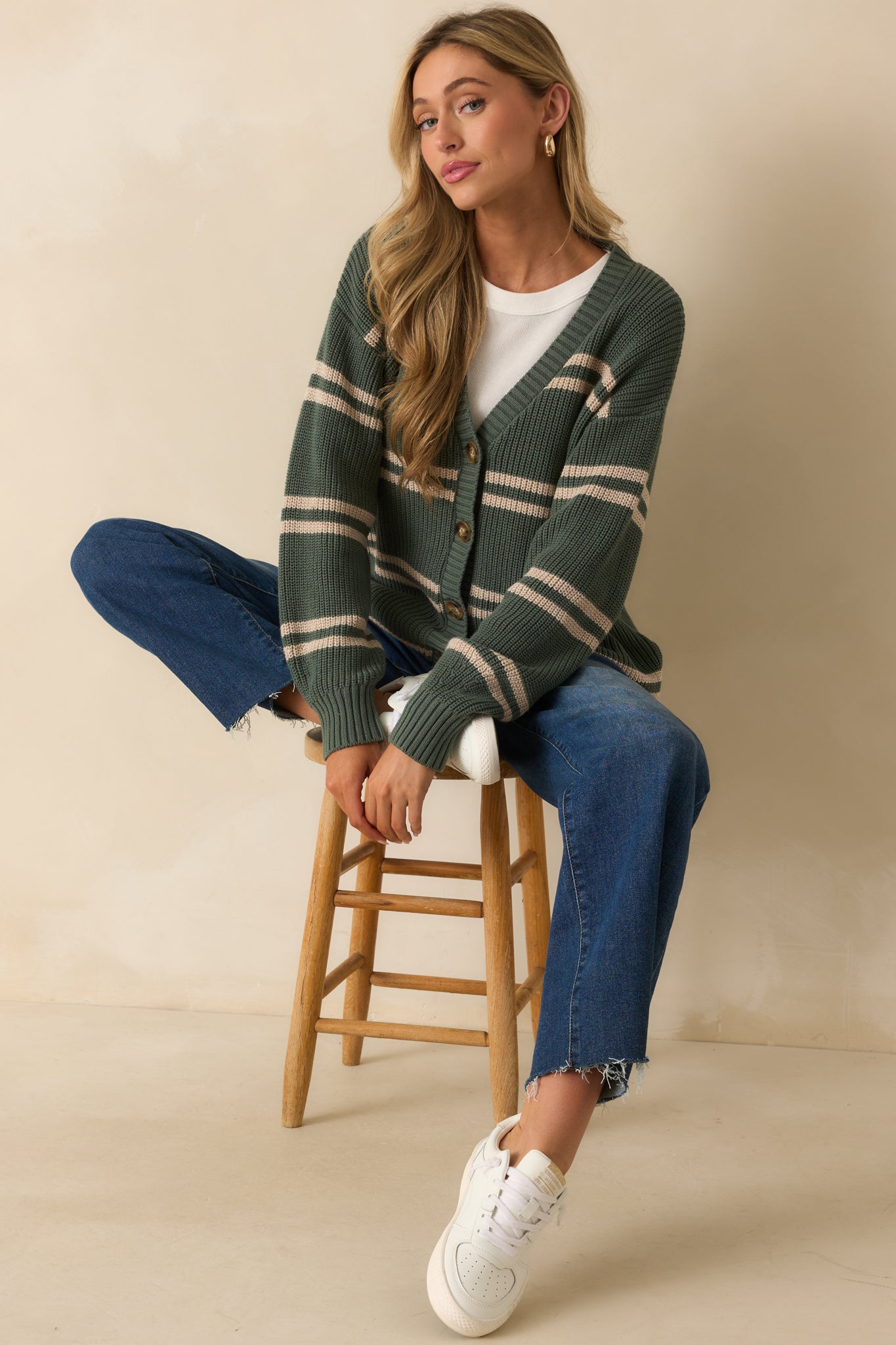 Up-close look at the button closure and ribbed hem on the green striped cardigan.