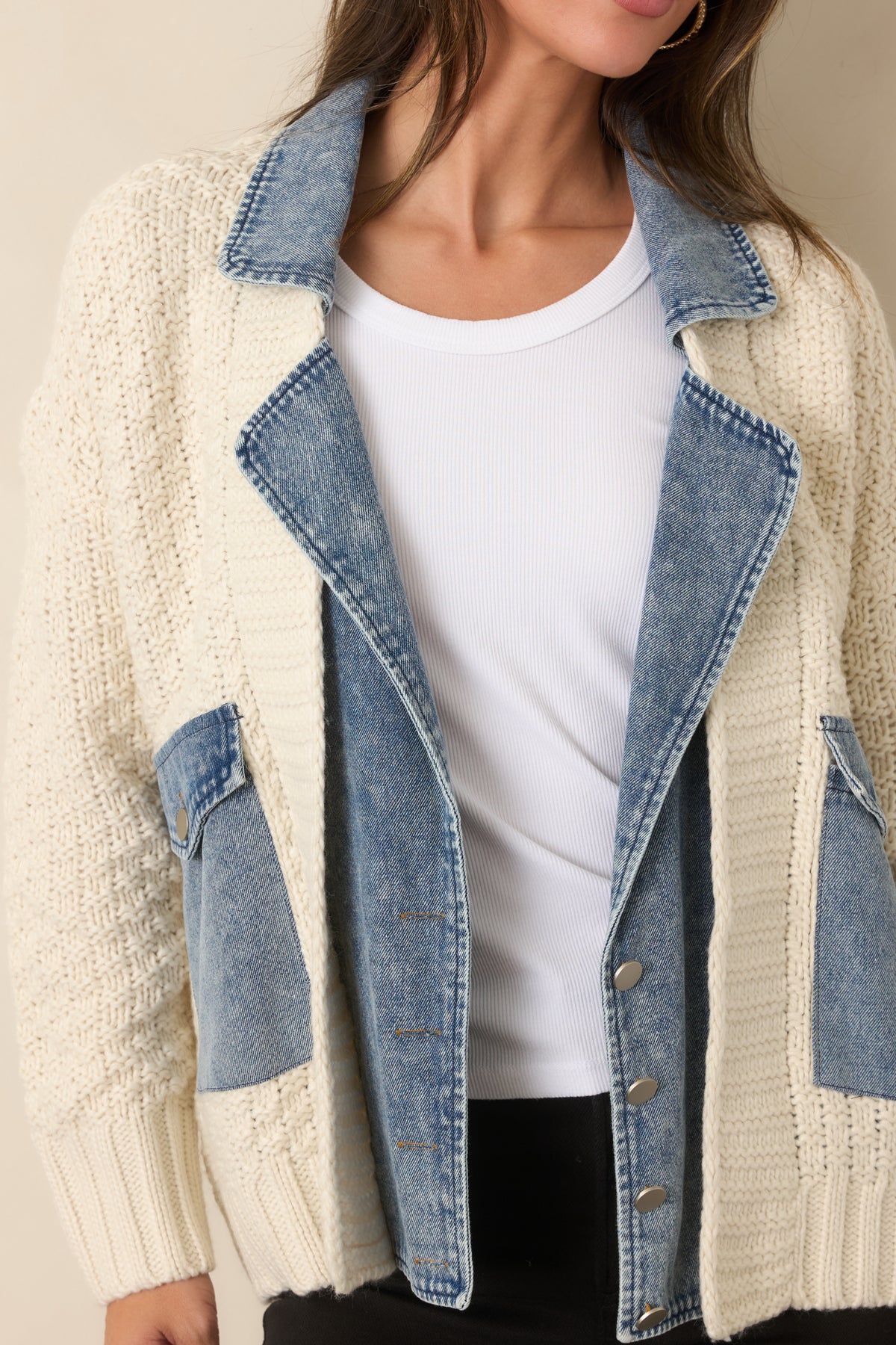 Close look at the blend of chunky ivory knit and structured denim trim highlighting the mixed-media design.
