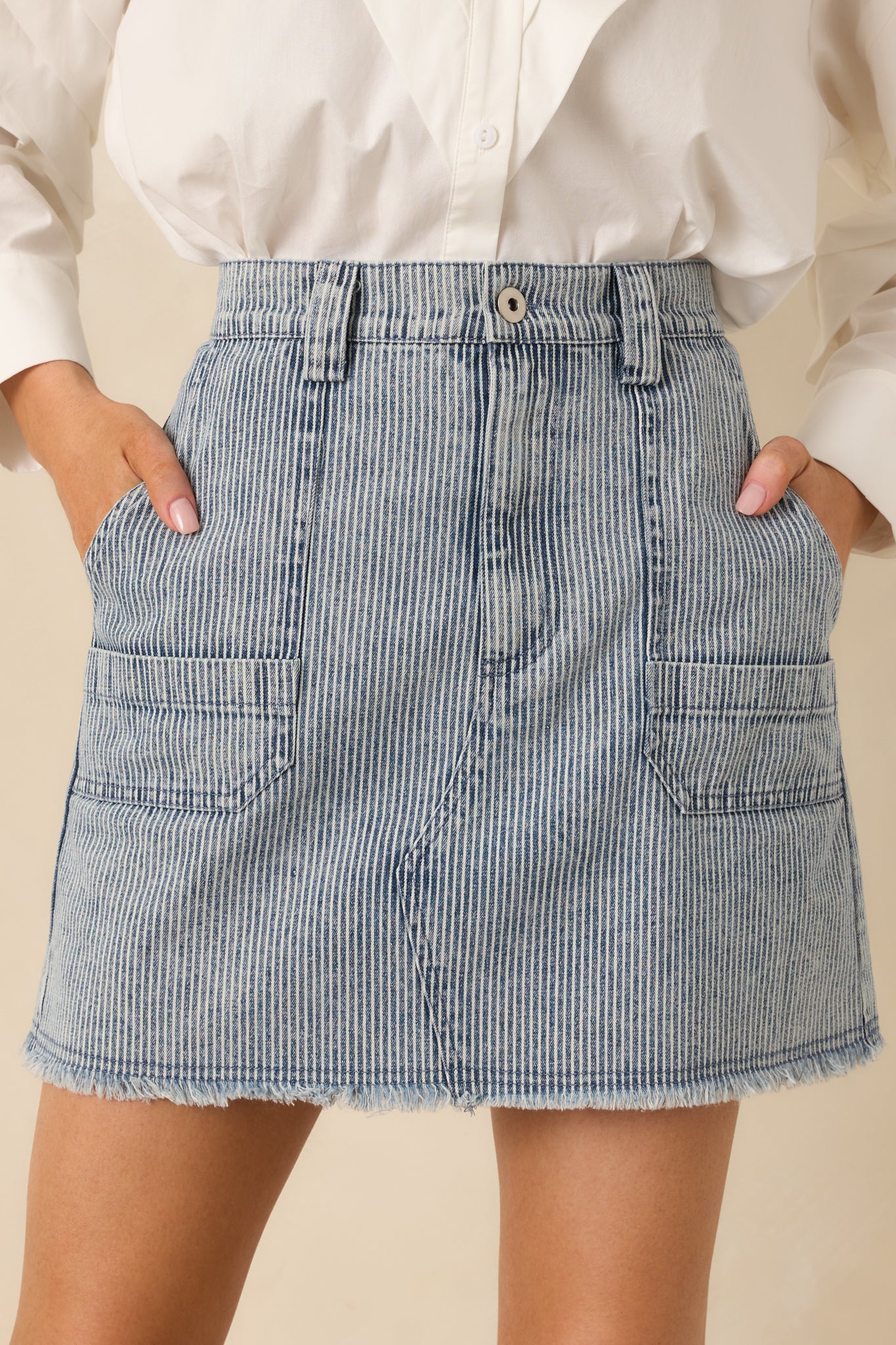 Detailed close-up of the blue stripe mini skirt showing the front button, zipper closure, and patch pocket stitching.