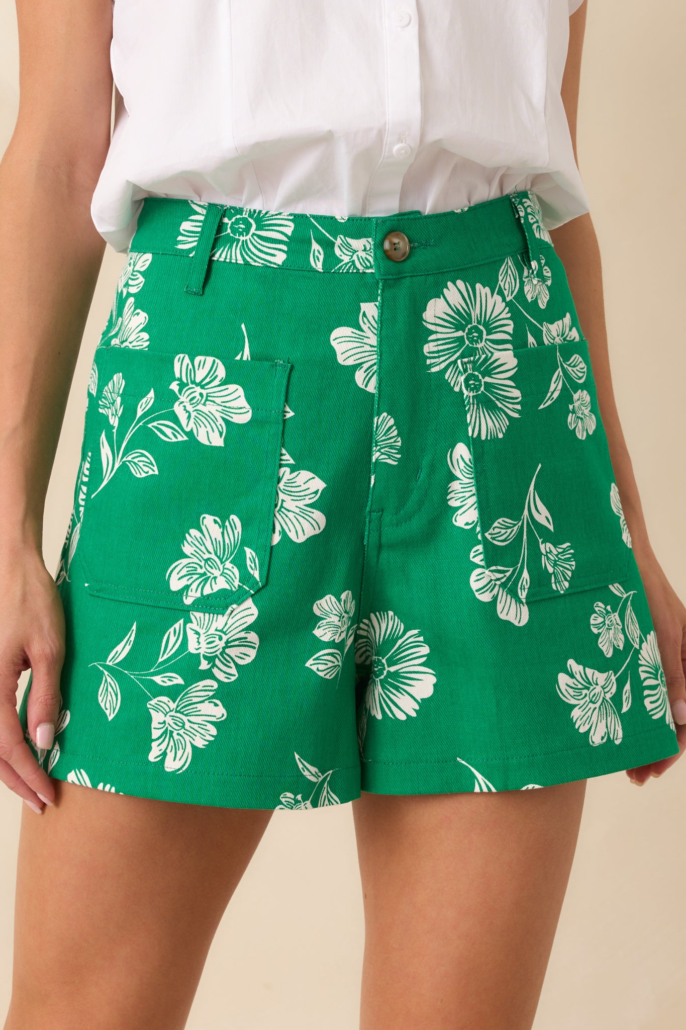 Close-up of the ivory floral print on the green fabric, highlighting stitching details and the texture of the material.
