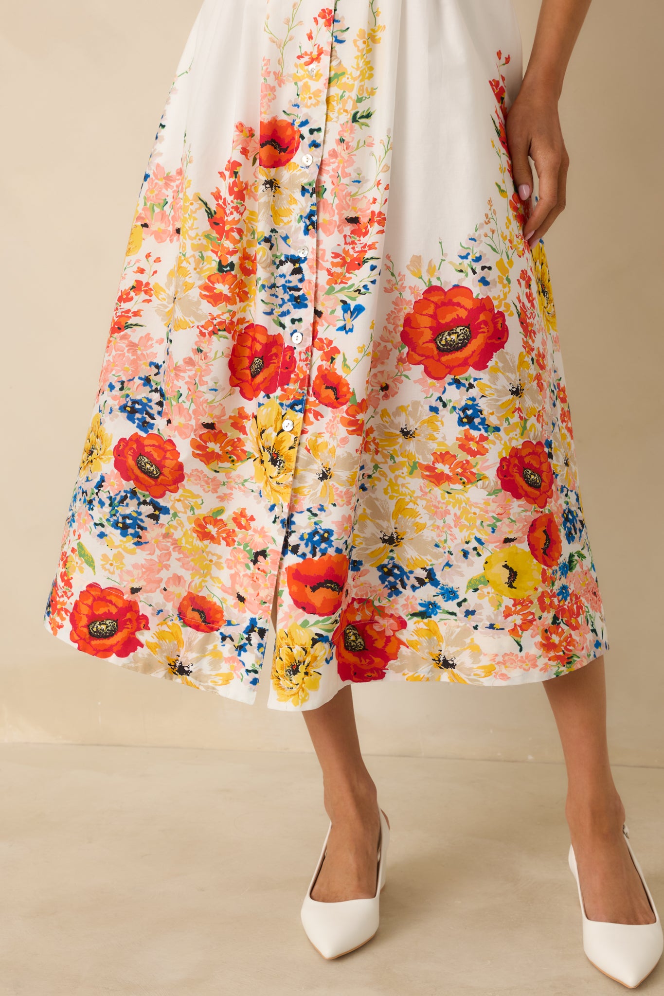 Close-up of the multicolor floral border print along the hem on the white cotton midi dress.