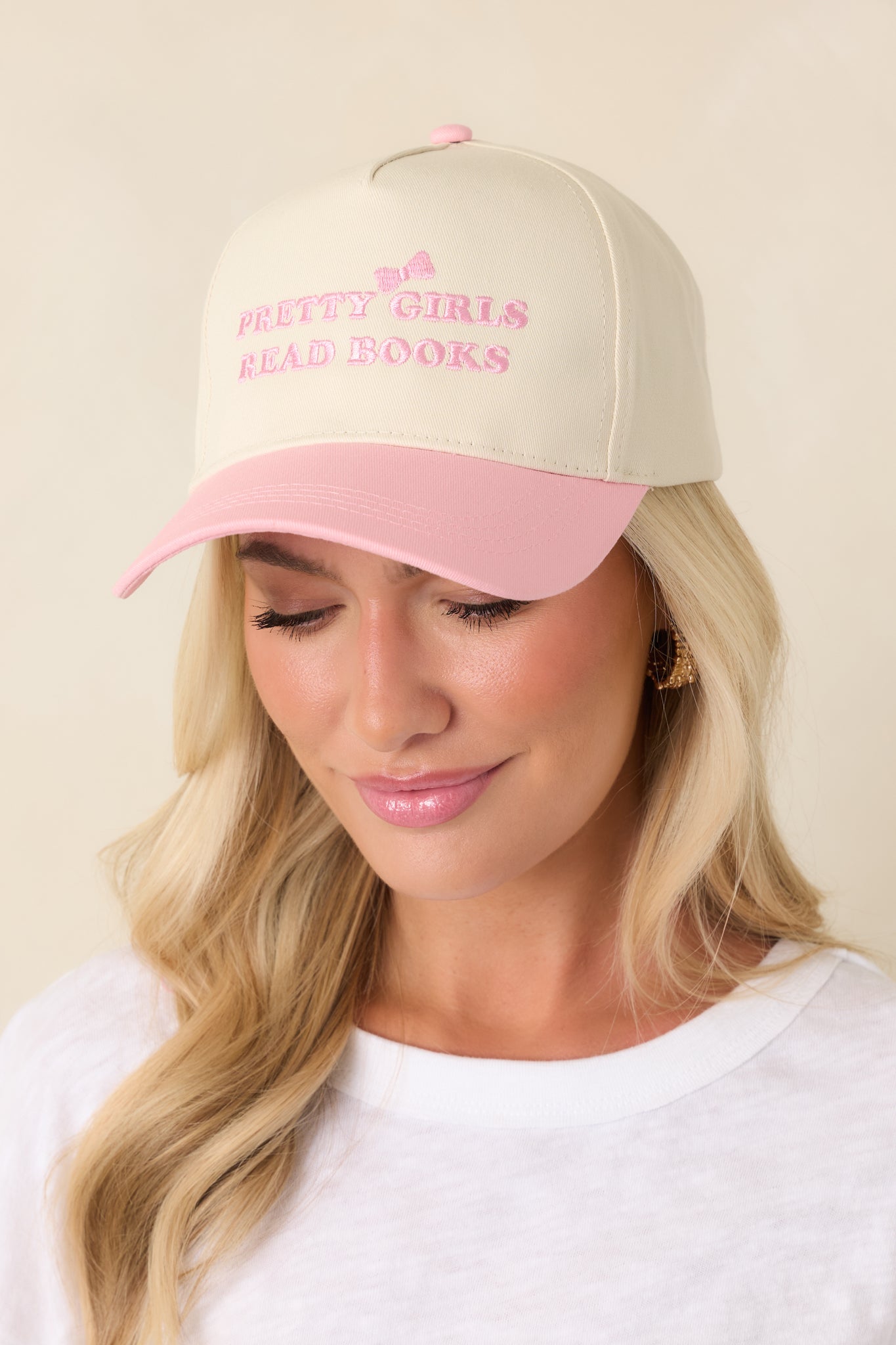 Detailed close-up of the pink embroidered text on the ivory crown, showing stitching detail and fabric texture.