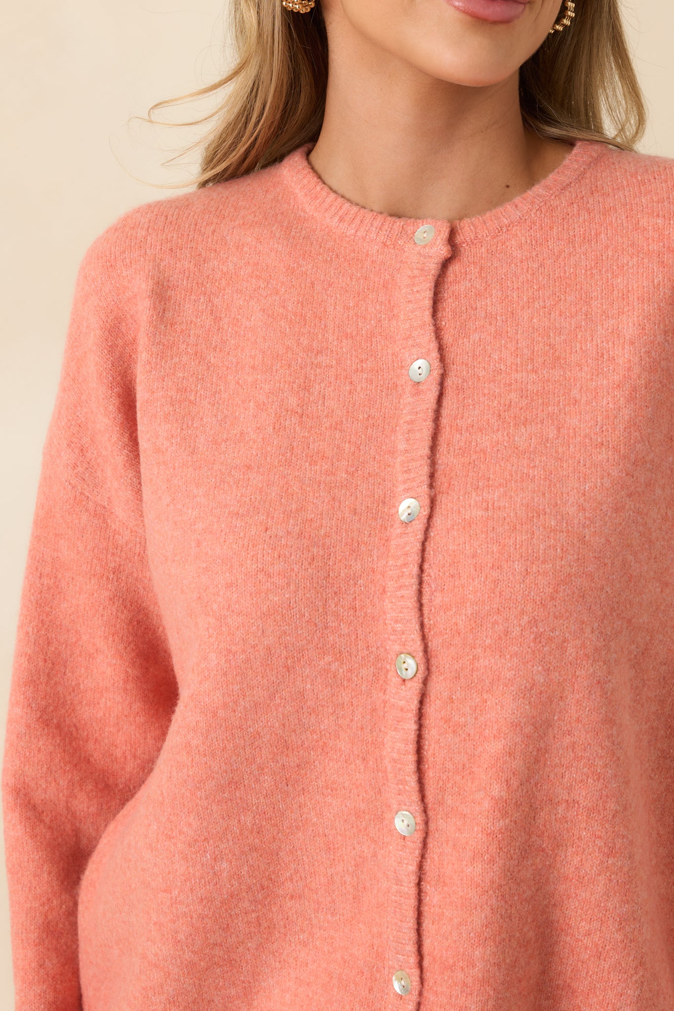 Close-up of the ribbed knit trim and button detailing, showcasing the soft texture of the orange fabric.
