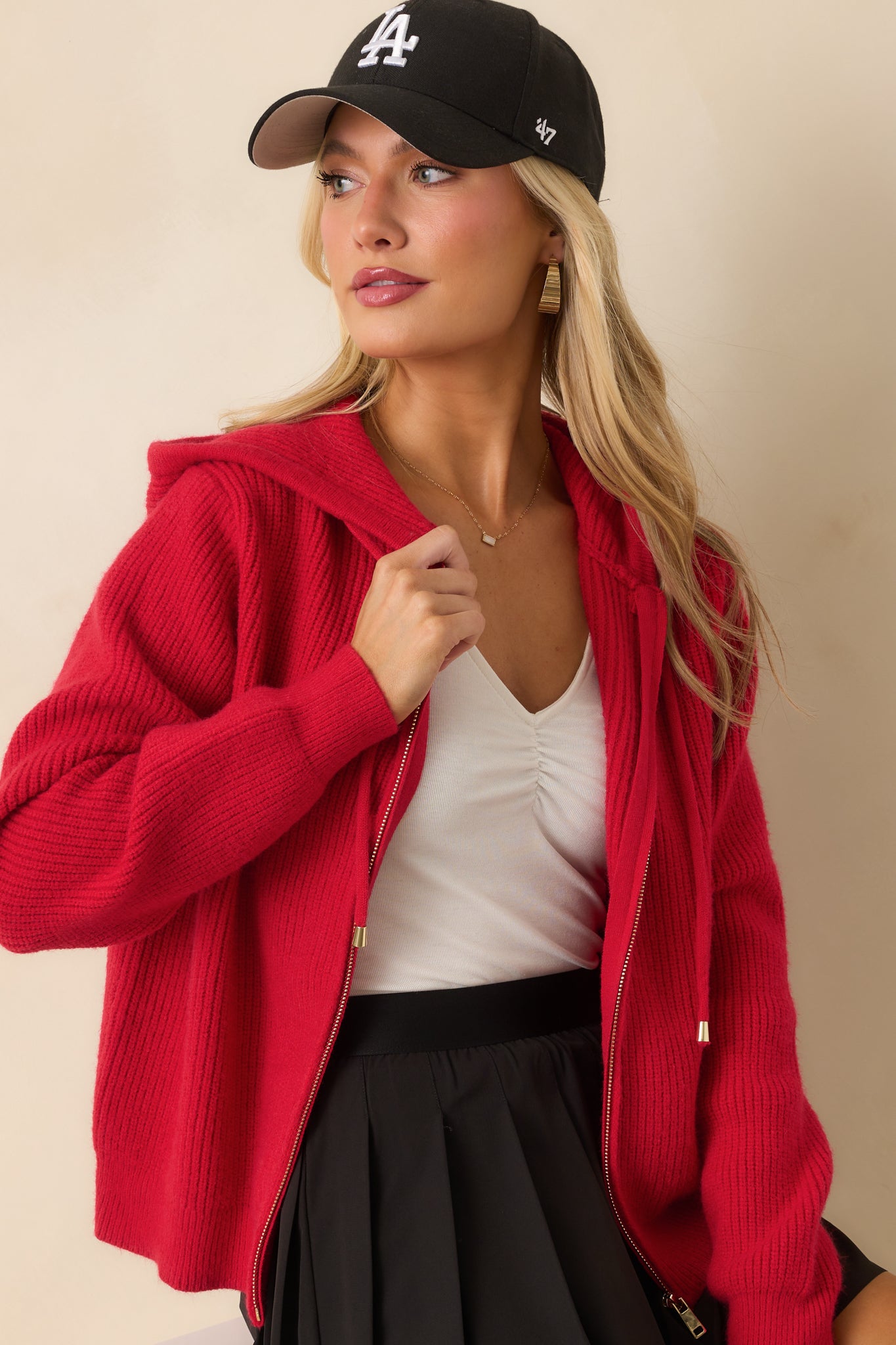 Close view of the red ribbed knit jacket focusing on zipper, hoodie, and textured fabric.