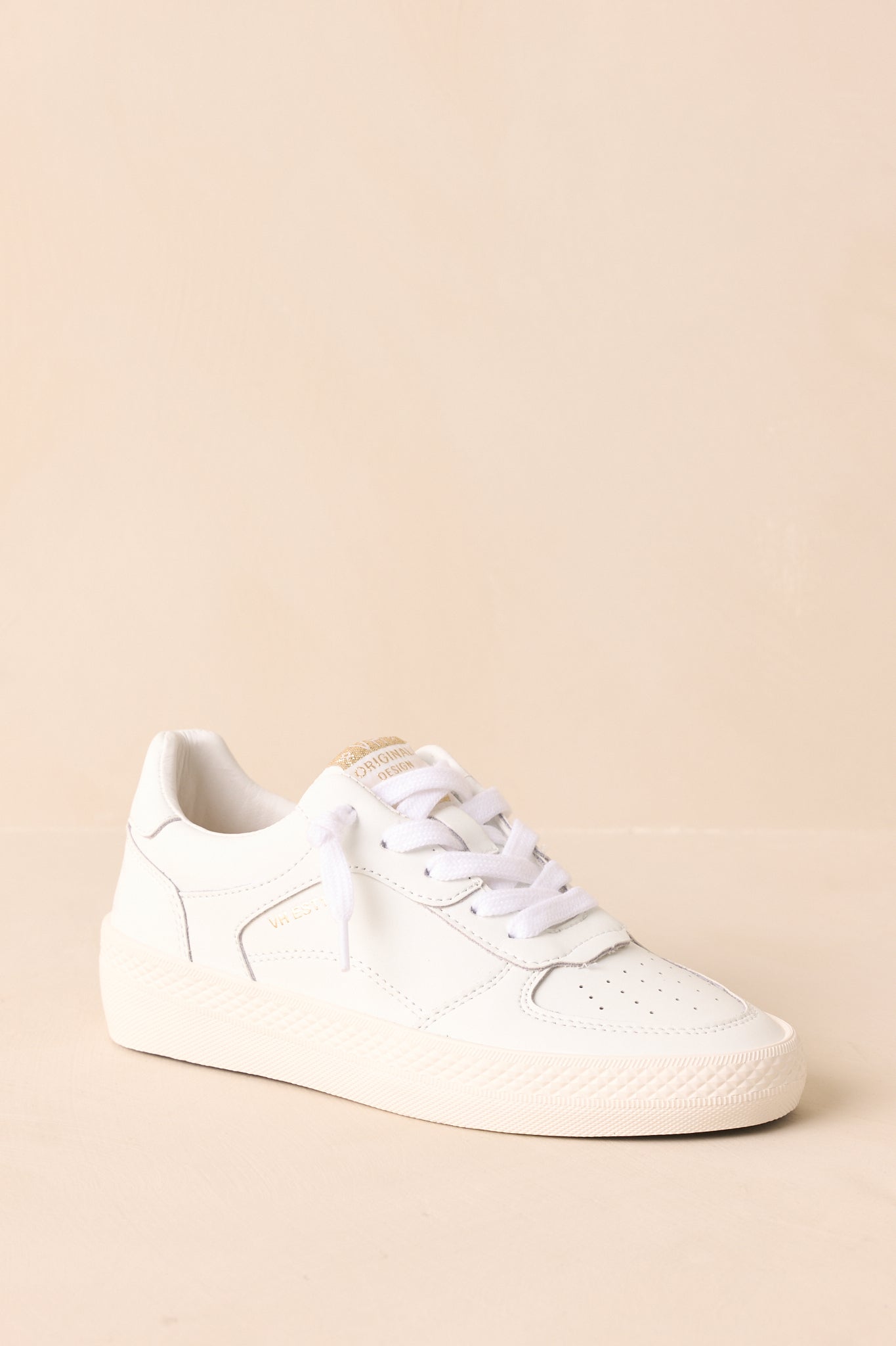 Close-up angle of white leather sneakers featuring distressed texture and white laces.