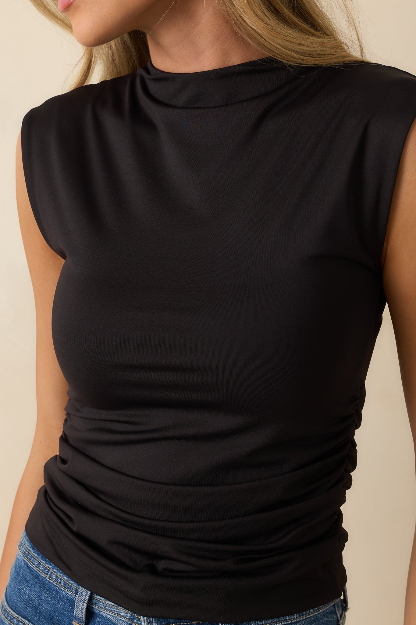 Close-up of black top’s ruched side seam and stretchy knit fabric texture.
