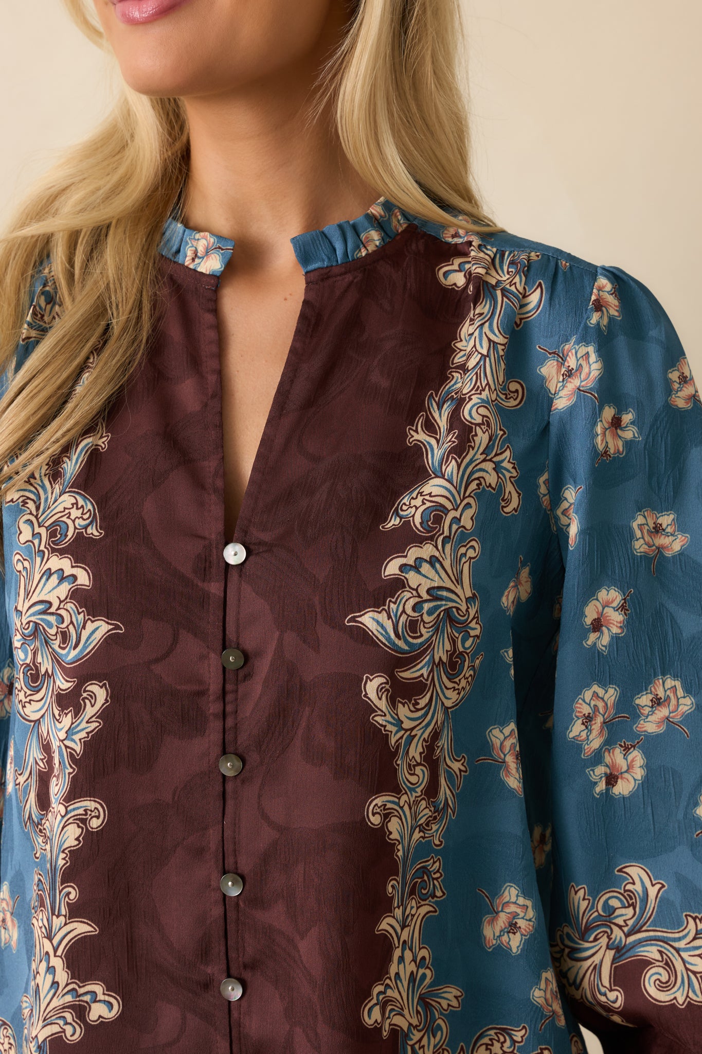 A close-up detail of the blue blouse showing a floral border print and button front.