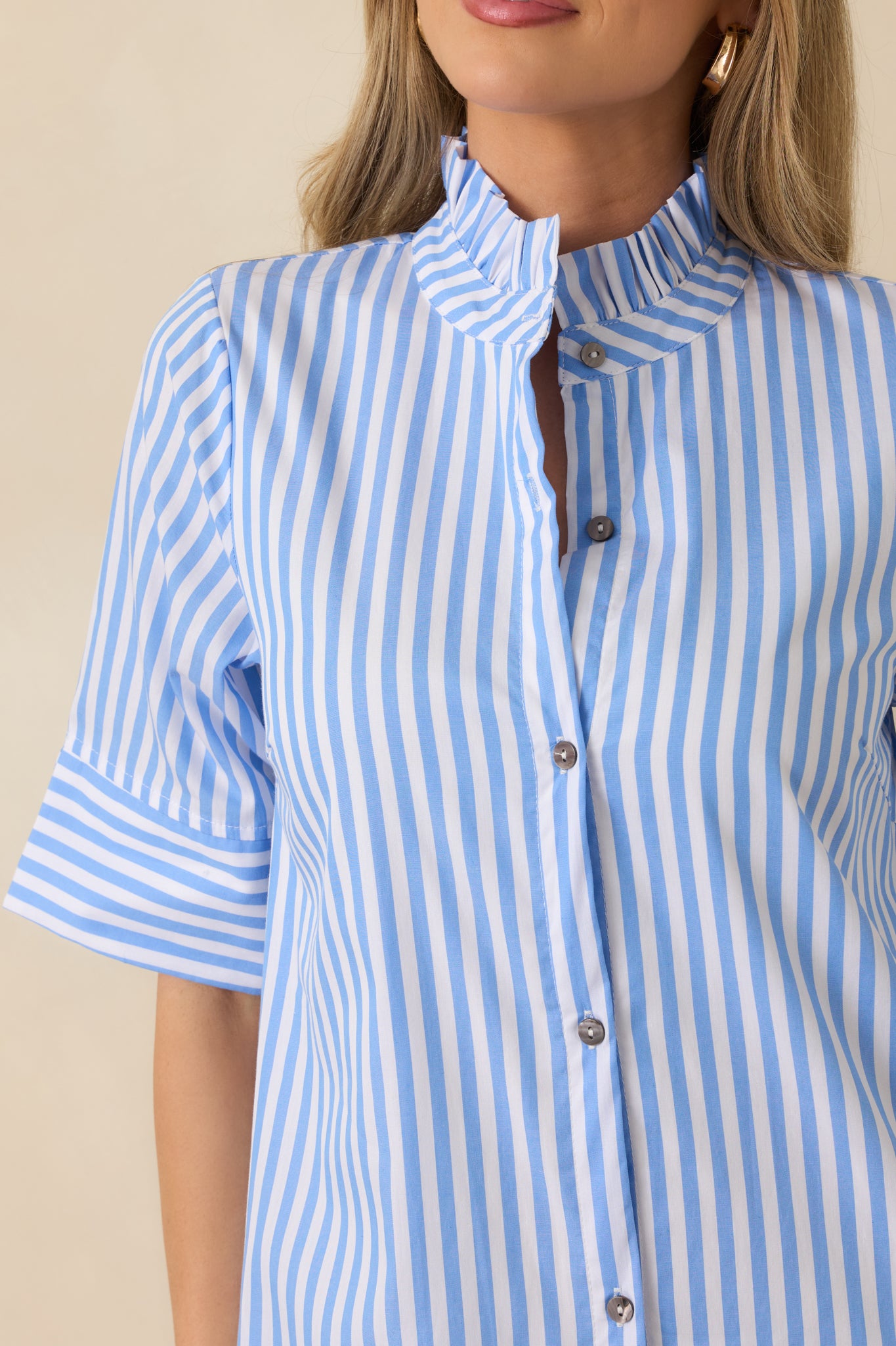 Close-up of blue striped shirt dress showing button-front detailing, ruffled collar, and woven texture.