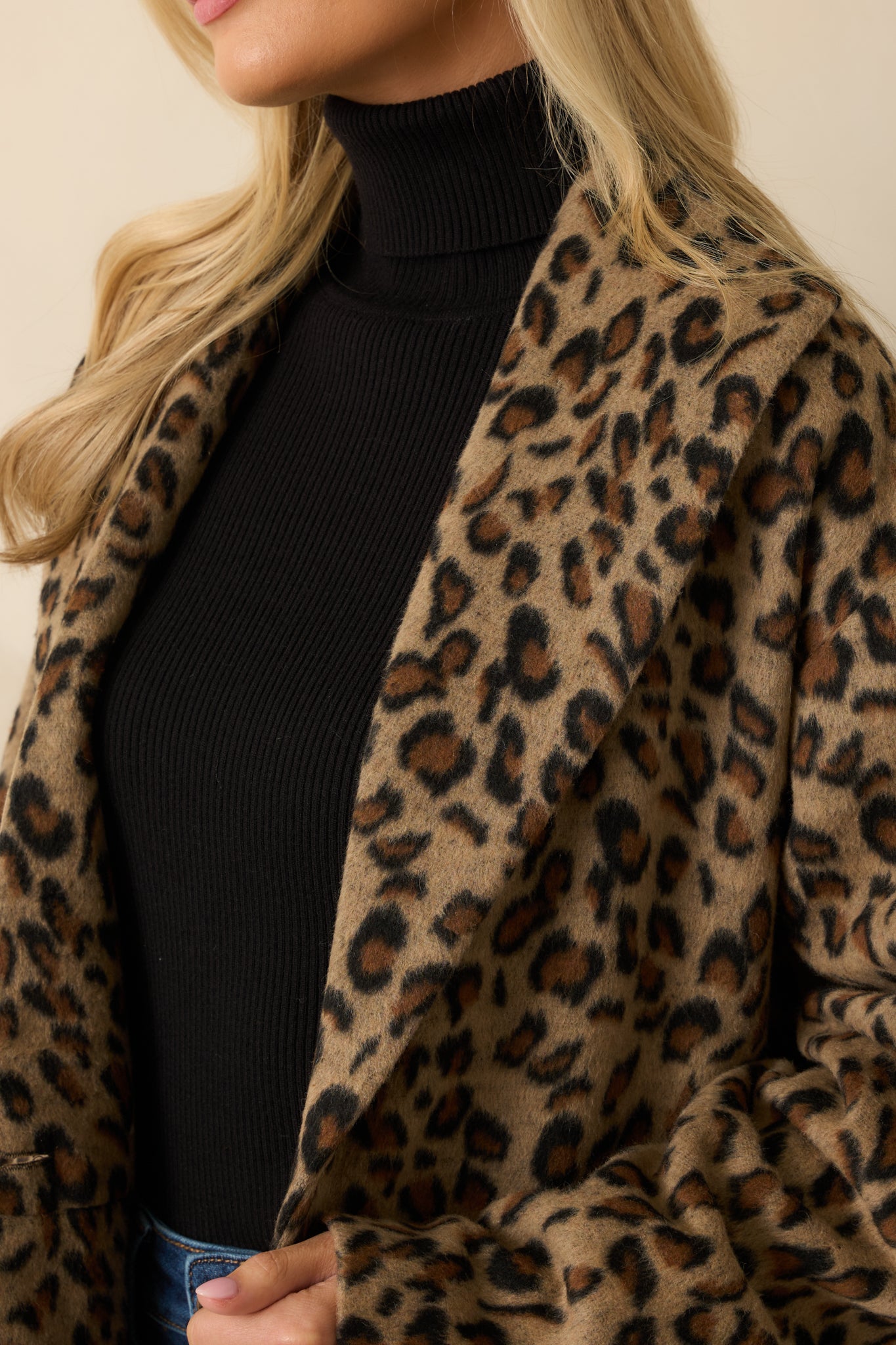 Close-up of button closure, notched collar, and brushed wool-blend texture on leopard print coat.