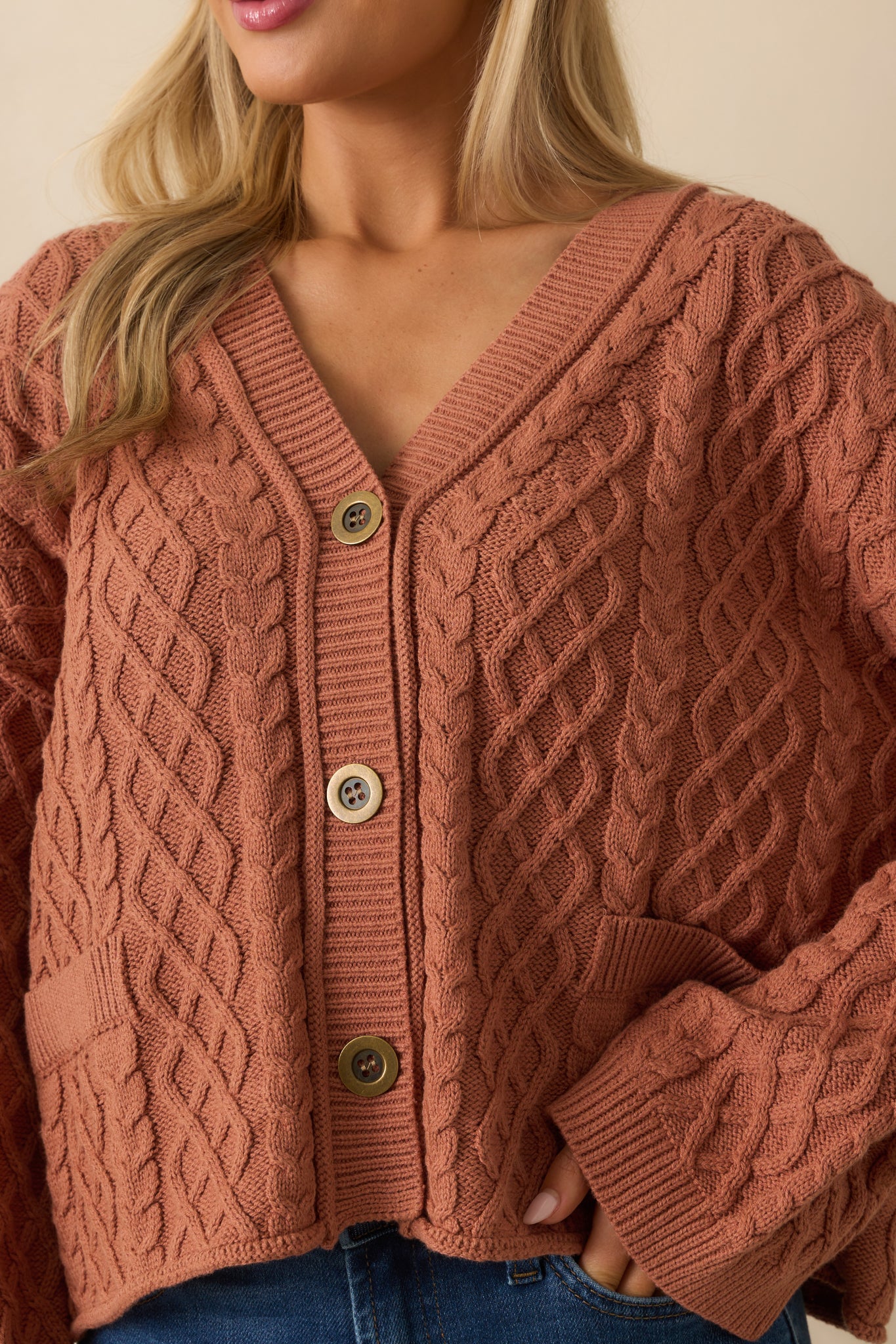 A close-up detail of the cable knit pattern and ribbed hems on the cardigan.