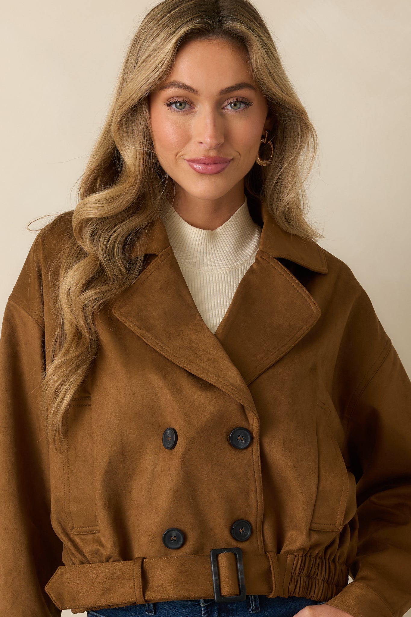 Close view of the camel trench coat’s double-breasted buttons and wide lapel collar.
