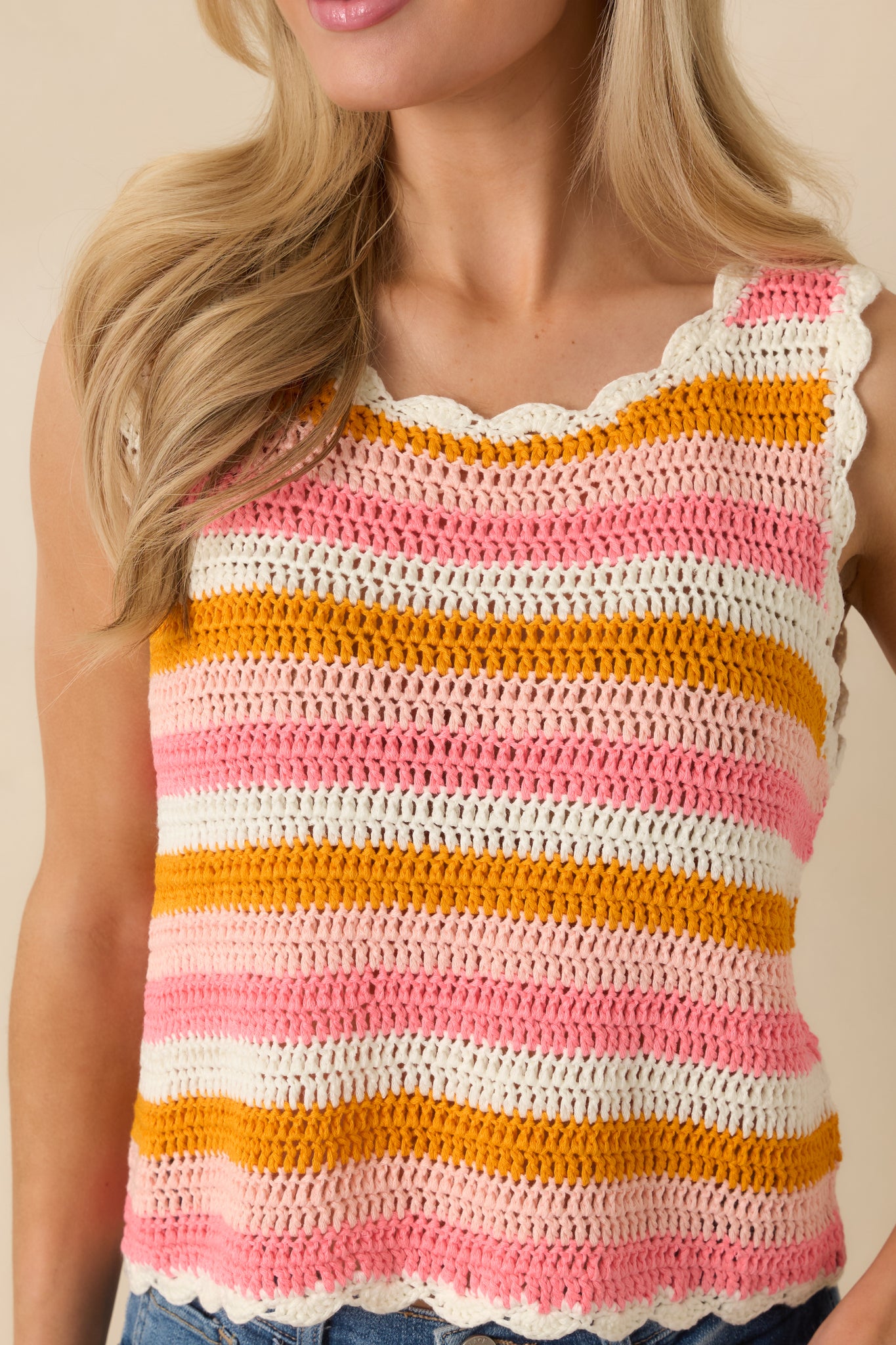 Close-up of the crochet knit showing open-weave texture, scalloped trim, and vibrant pink and orange stripe detailing.