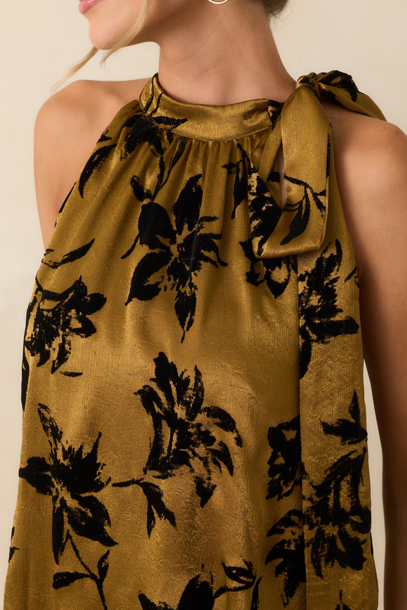 Close-up of the dark gold satin fabric showing the burnout floral velvet pattern and rich texture.