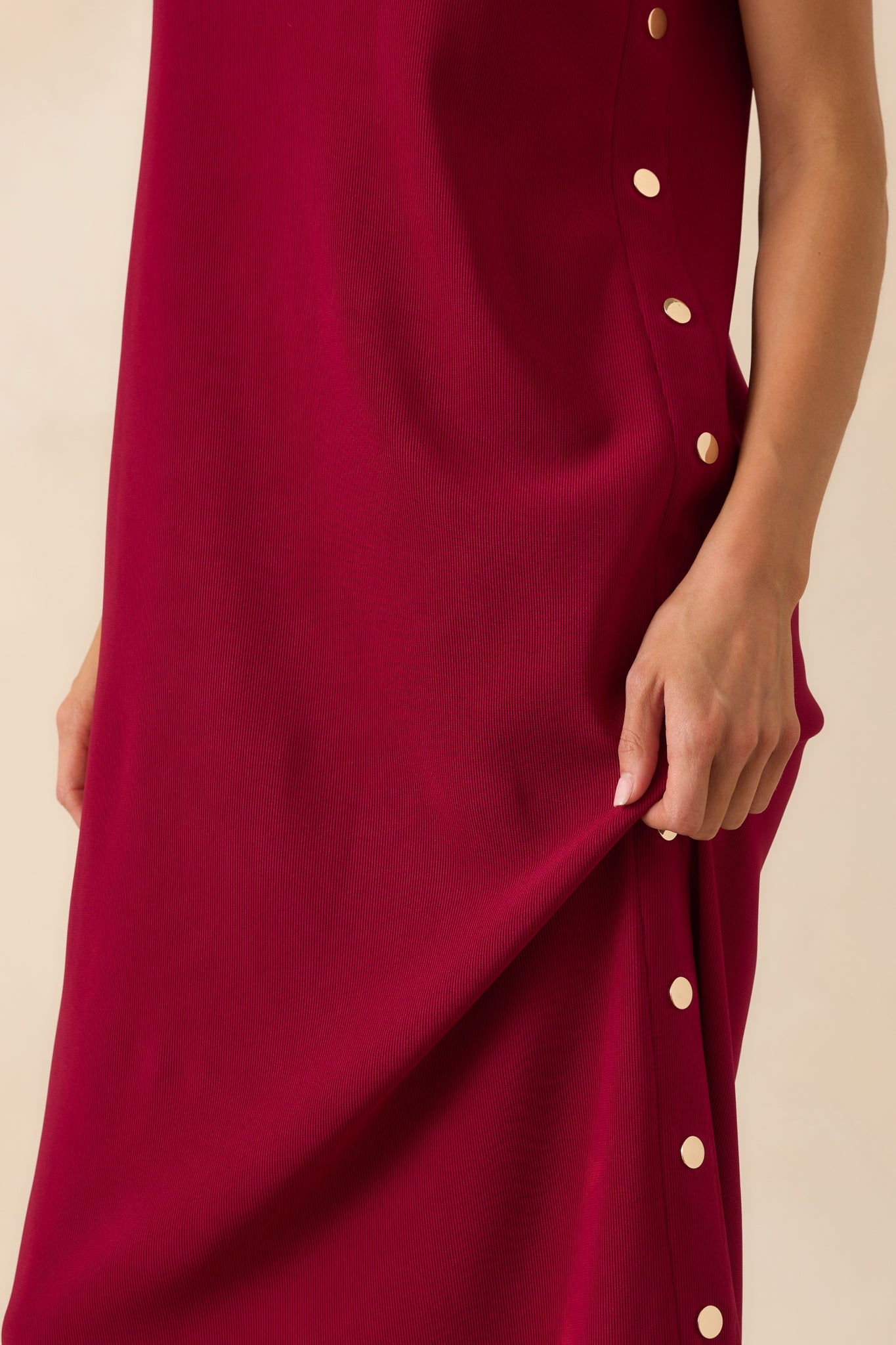 Close-up detail of the decorative gold buttons along the side seam of the burgundy maxi dress.